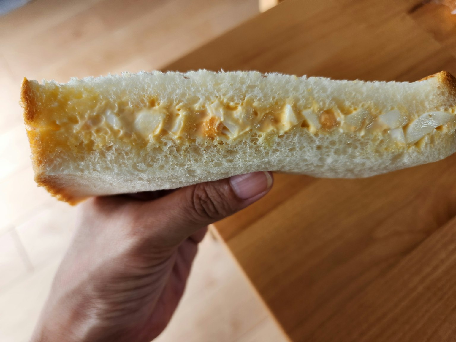 Immagine di una sezione trasversale di pane tenuta in mano che mostra una consistenza morbida e un ripieno