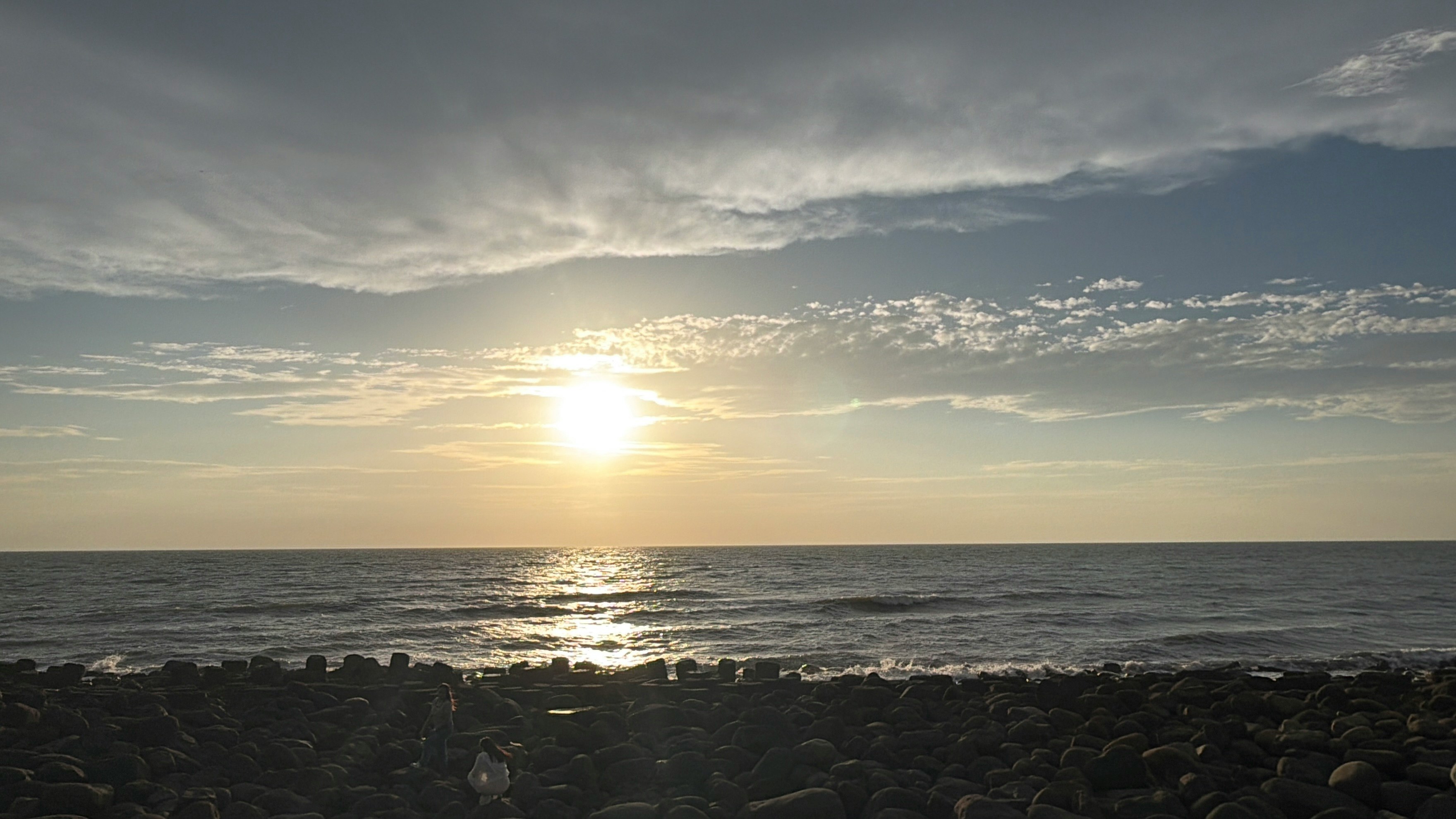 夕日に照らされる海と岩場の海岸
