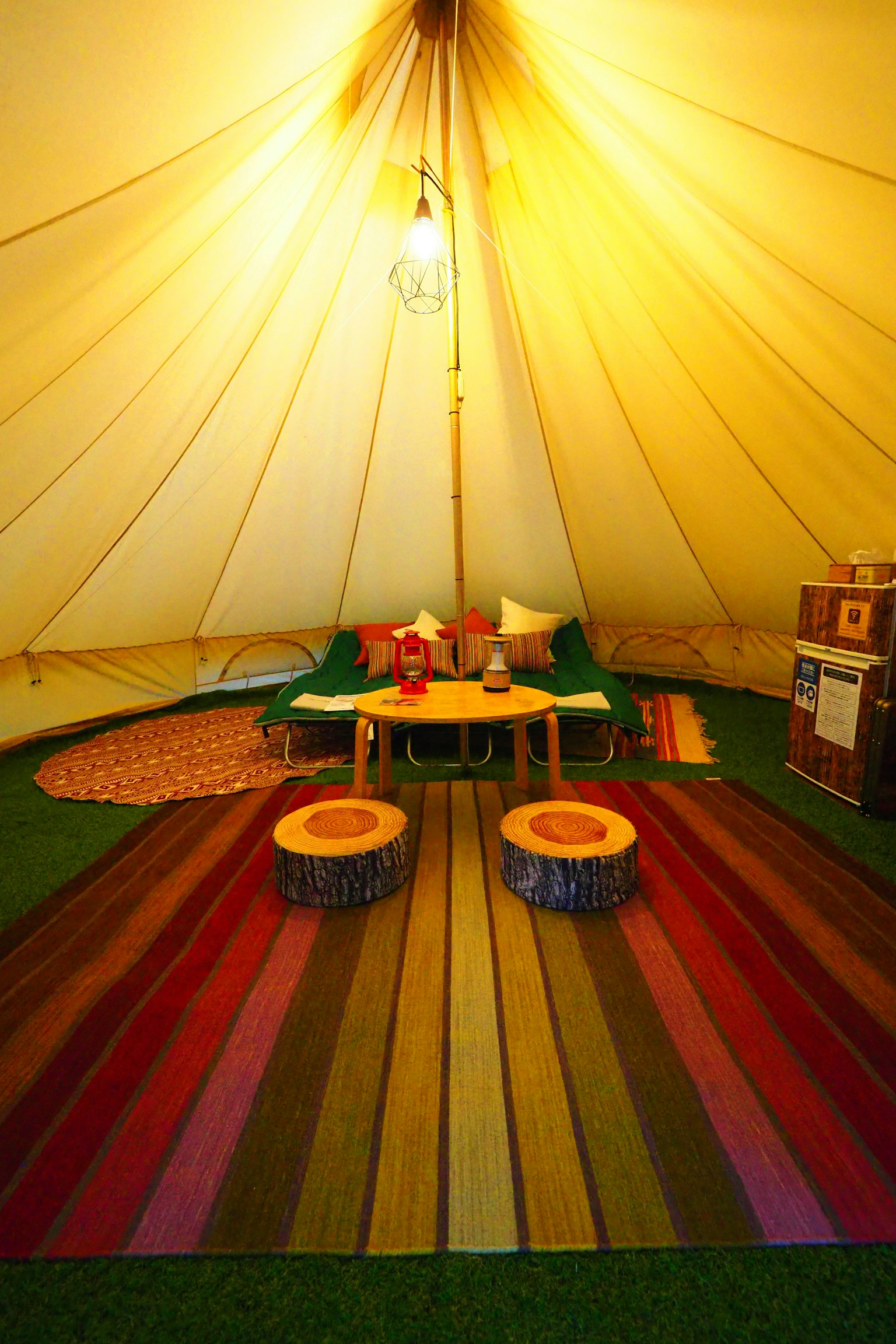 Interno accogliente di una tenda con un tappeto colorato e sgabelli in legno