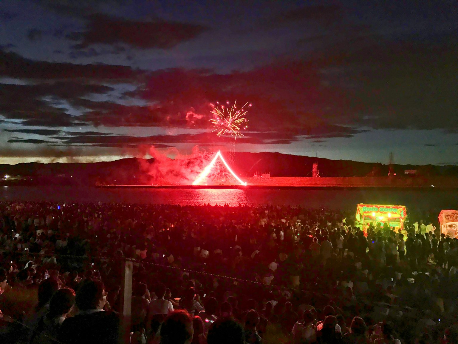 Foule profitant d'un spectacle de feux d'artifice sur l'eau la nuit