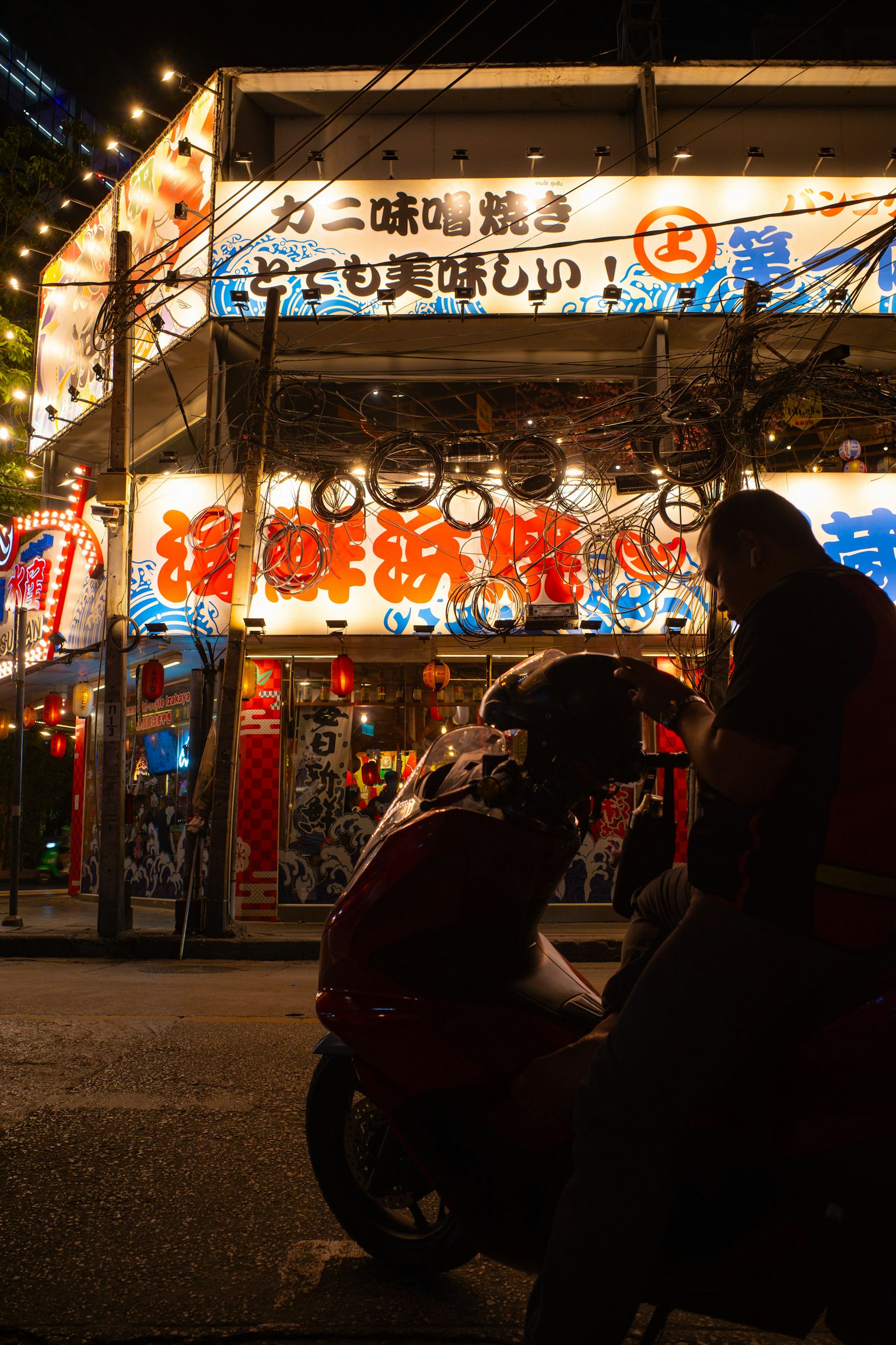 夜间灯光明亮的餐厅外观和附近坐着的人们