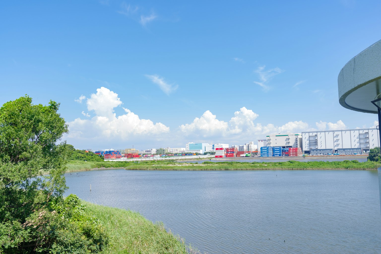 Dòng sông dưới bầu trời xanh và mây trắng bên cạnh các tòa nhà công nghiệp