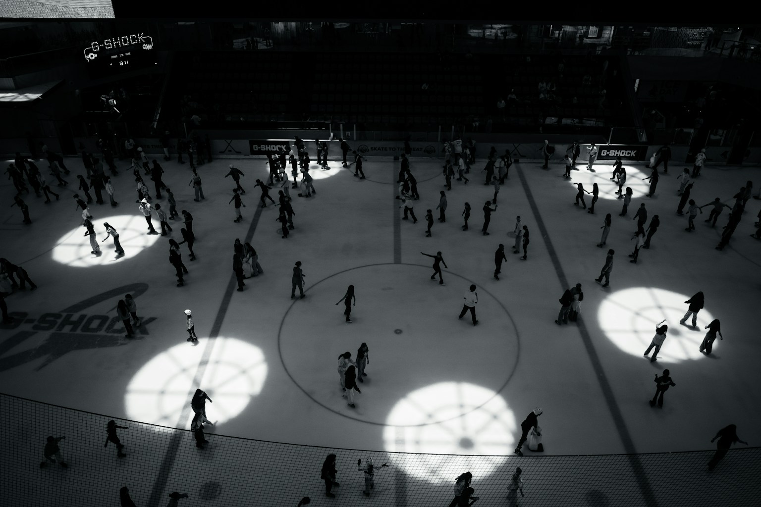 Kerumunan orang yang berseluncur di atas es dengan pola cahaya melingkar