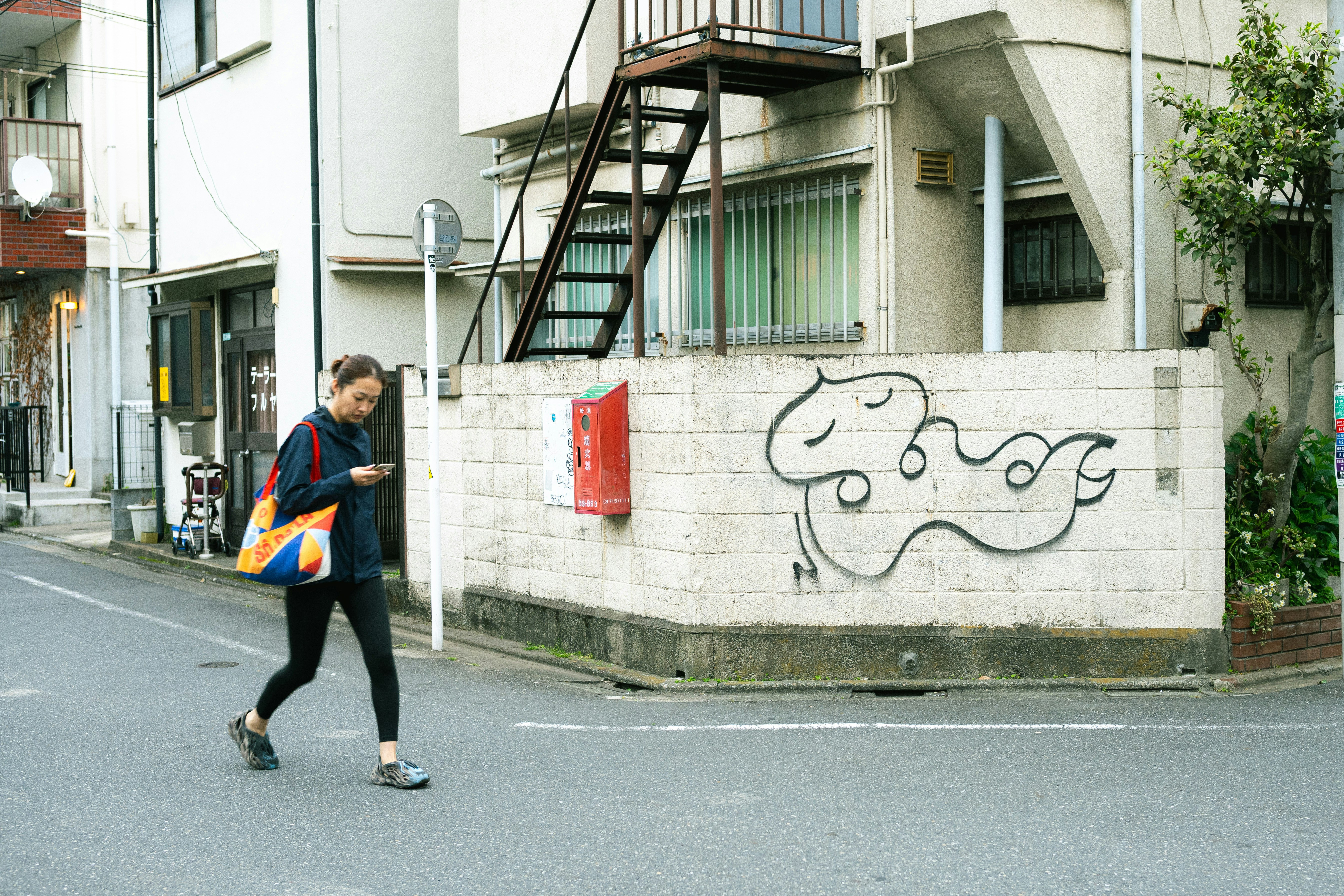 路地の壁に描かれた落書きと買い物袋を持つ人物のある街角