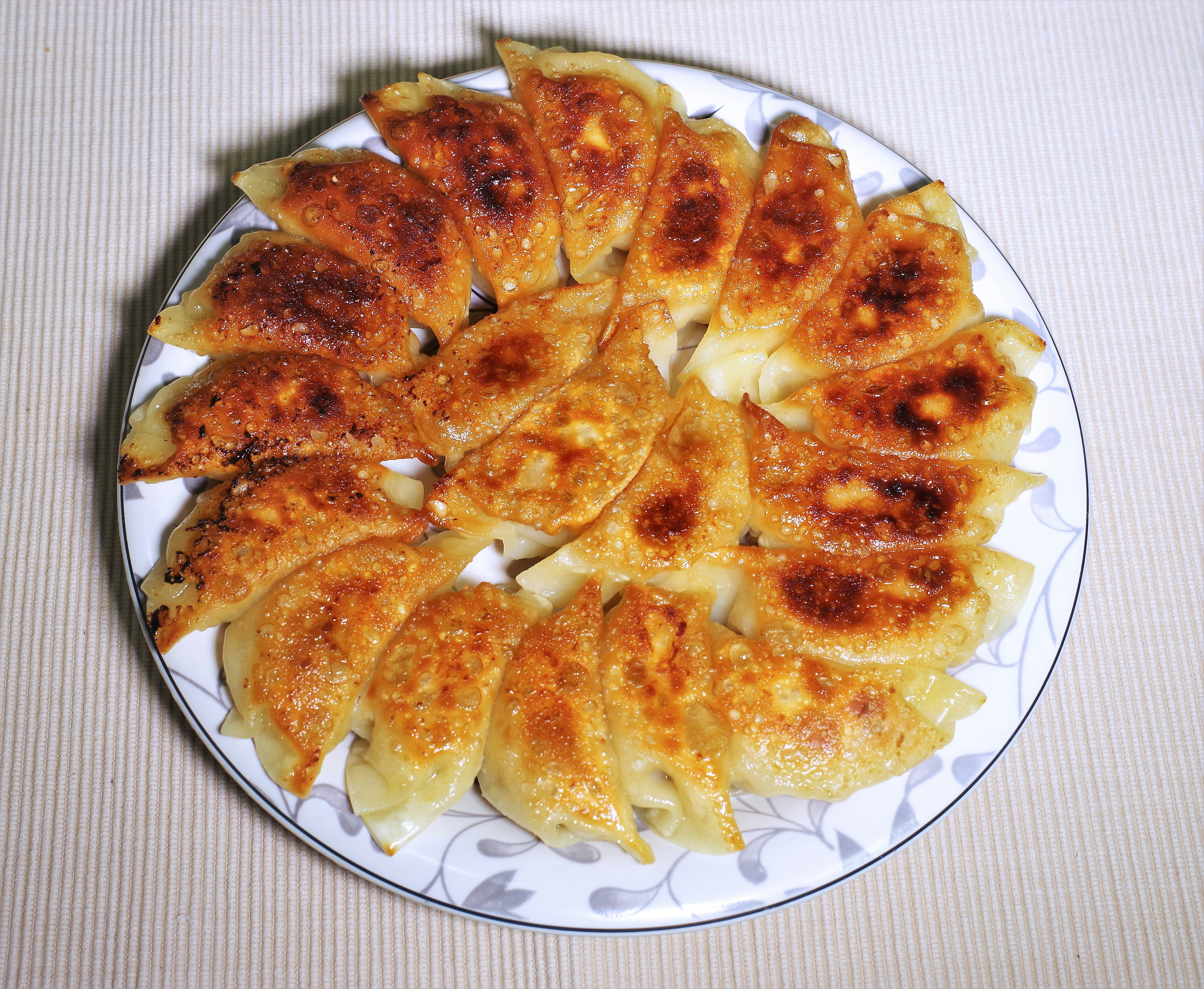 焼き目のついた餃子が大皿に並ぶ中華料理の食事