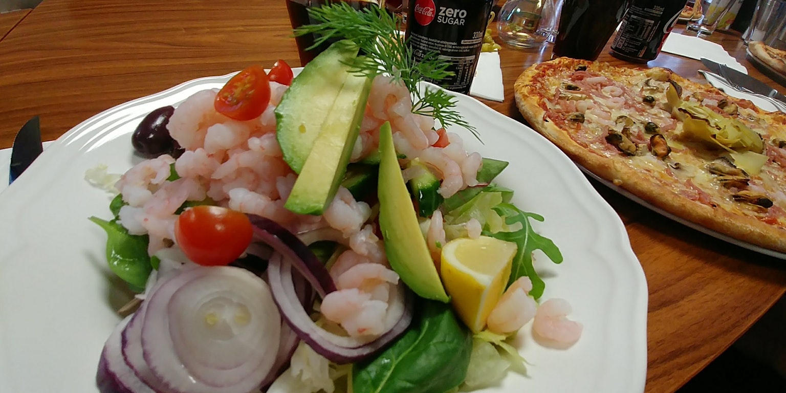 Insalata di gamberi e avocado con pizza su un tavolo di legno
