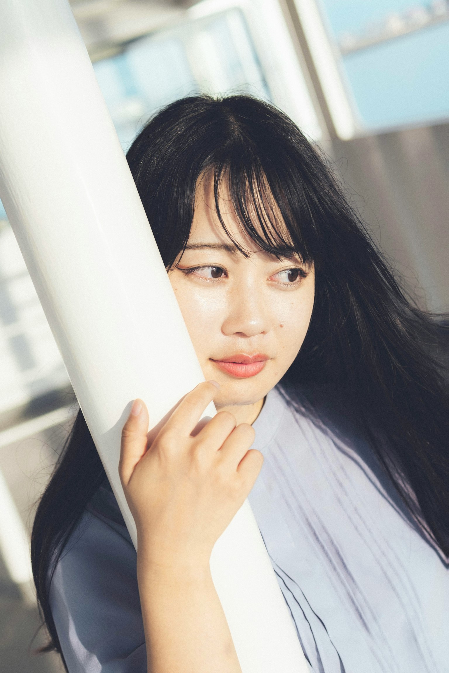 Portrait of a woman leaning against a white pillar