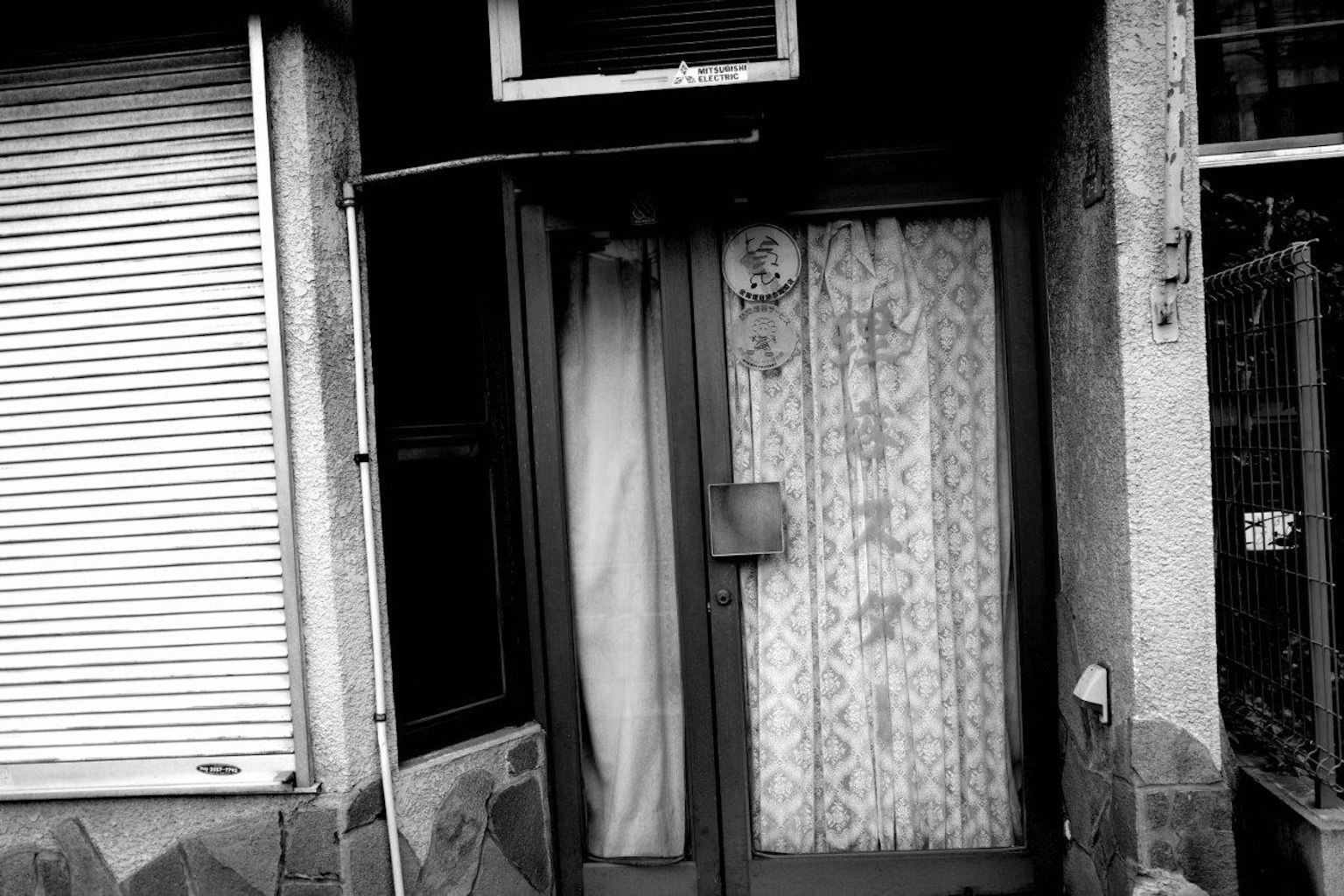 Exterior de un edificio antiguo con una puerta y una ventana en blanco y negro