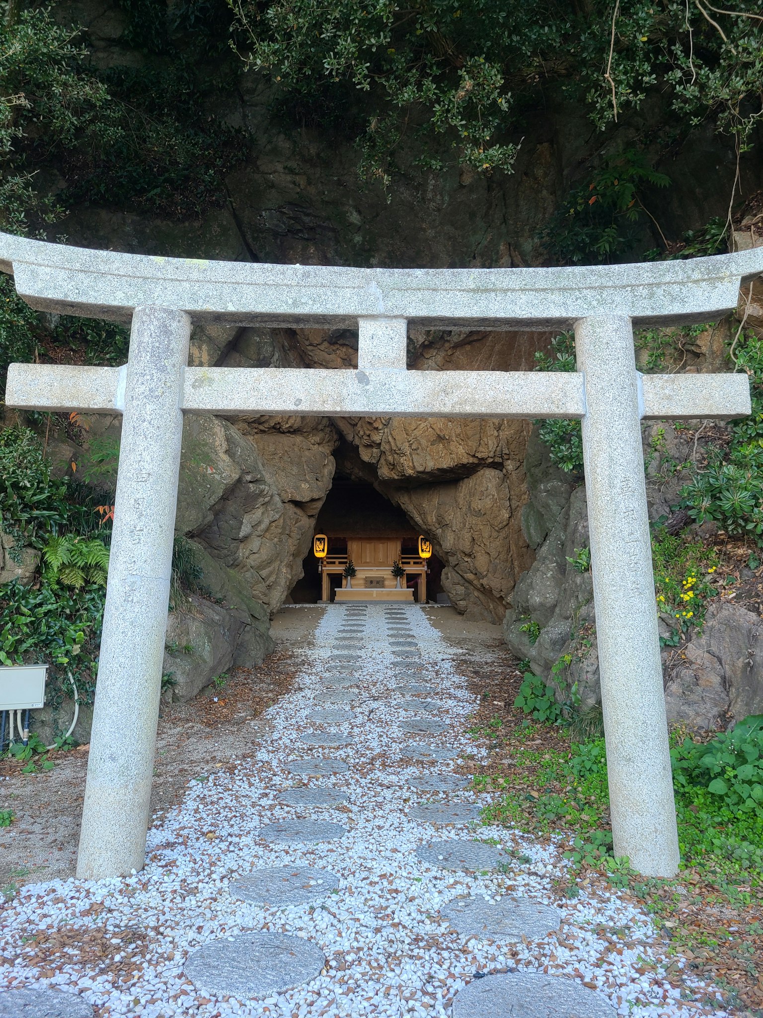 Entrée d'un sanctuaire avec un torii menant à une grotte rocheuse