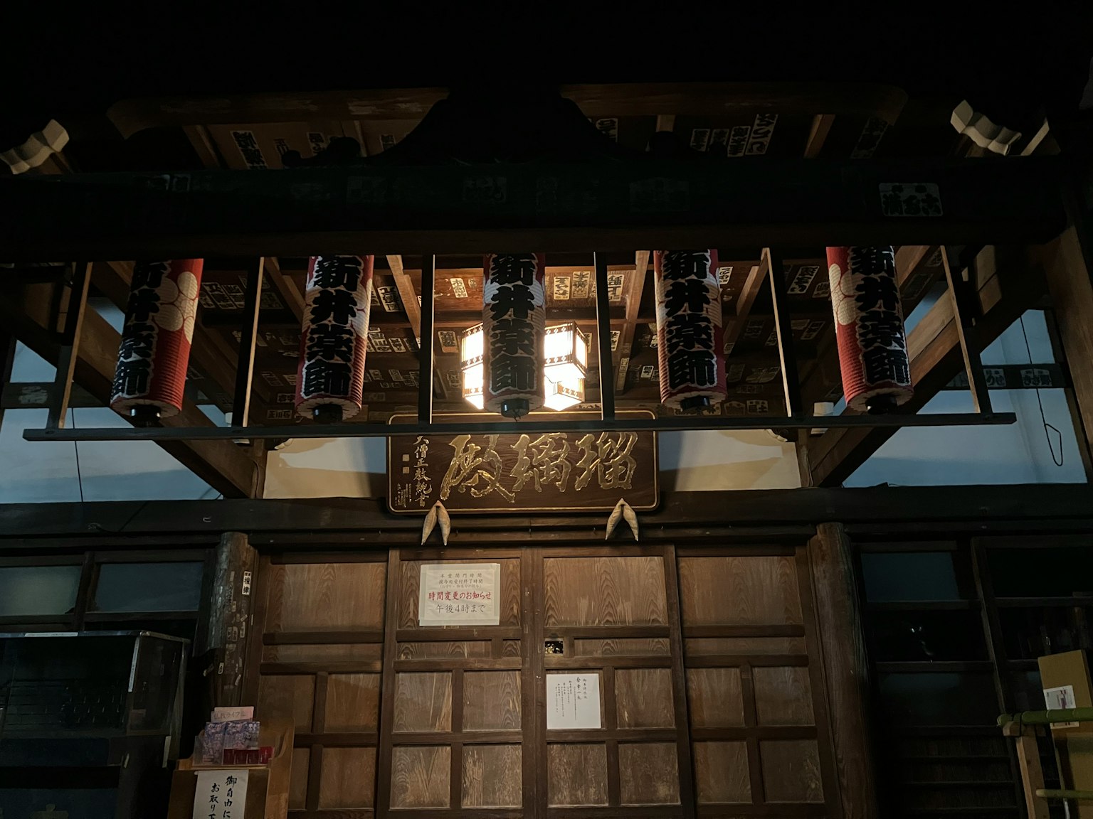 Entrada de un edificio japonés tradicional con puerta de madera iluminada y letrero decorativo
