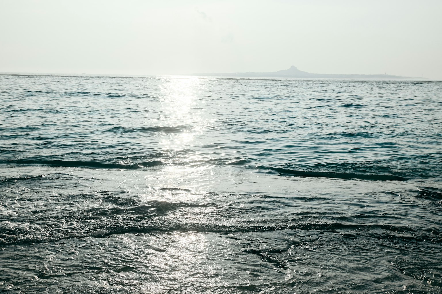 平靜的海面反射著光線，遠處可見一個島嶼