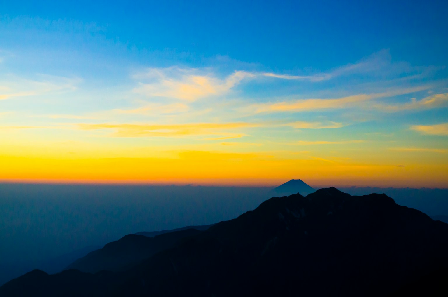 Langit matahari terbenam yang menakjubkan dengan siluet pegunungan
