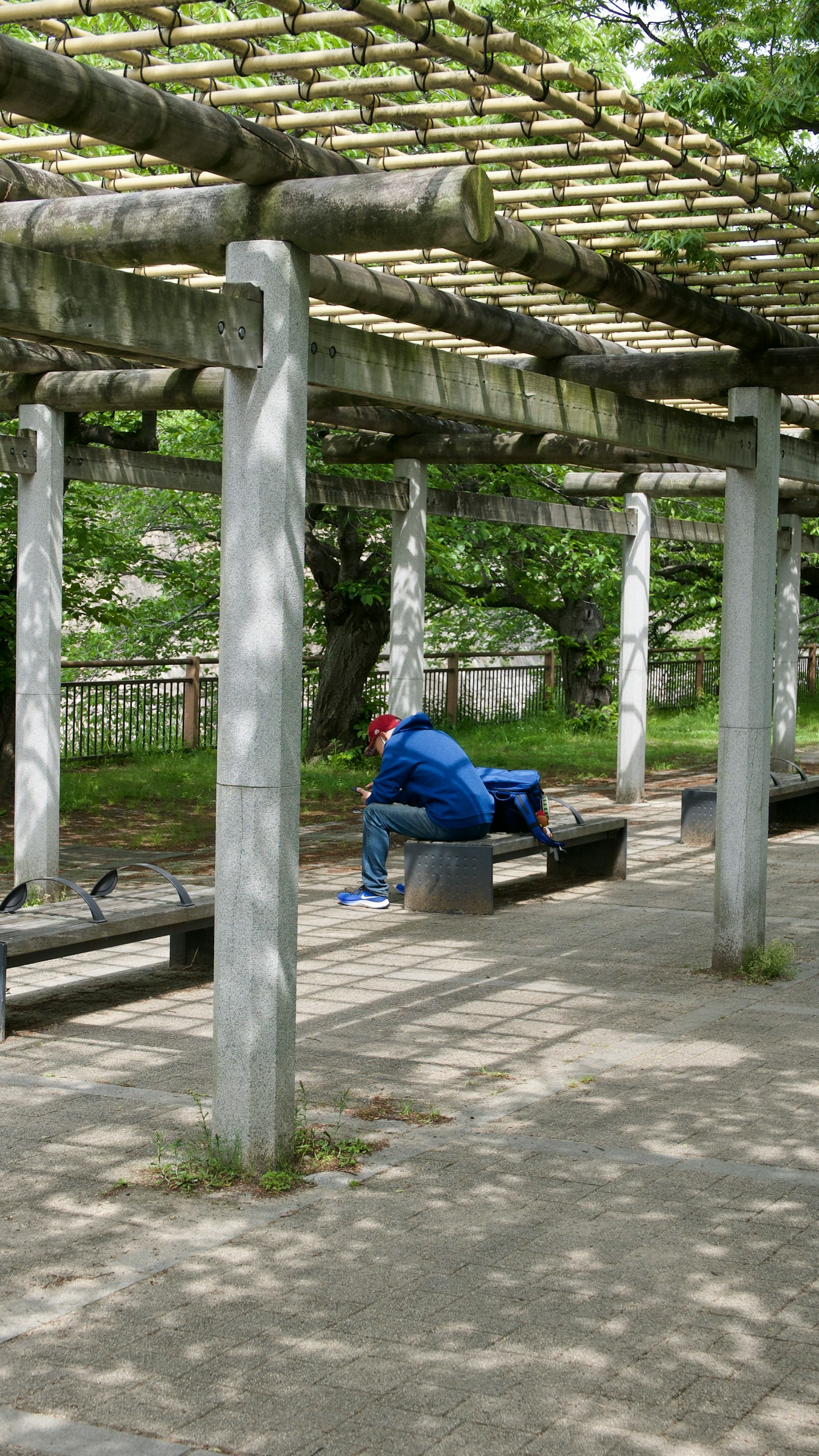 Una persona in abiti blu seduta su una panchina in un parco