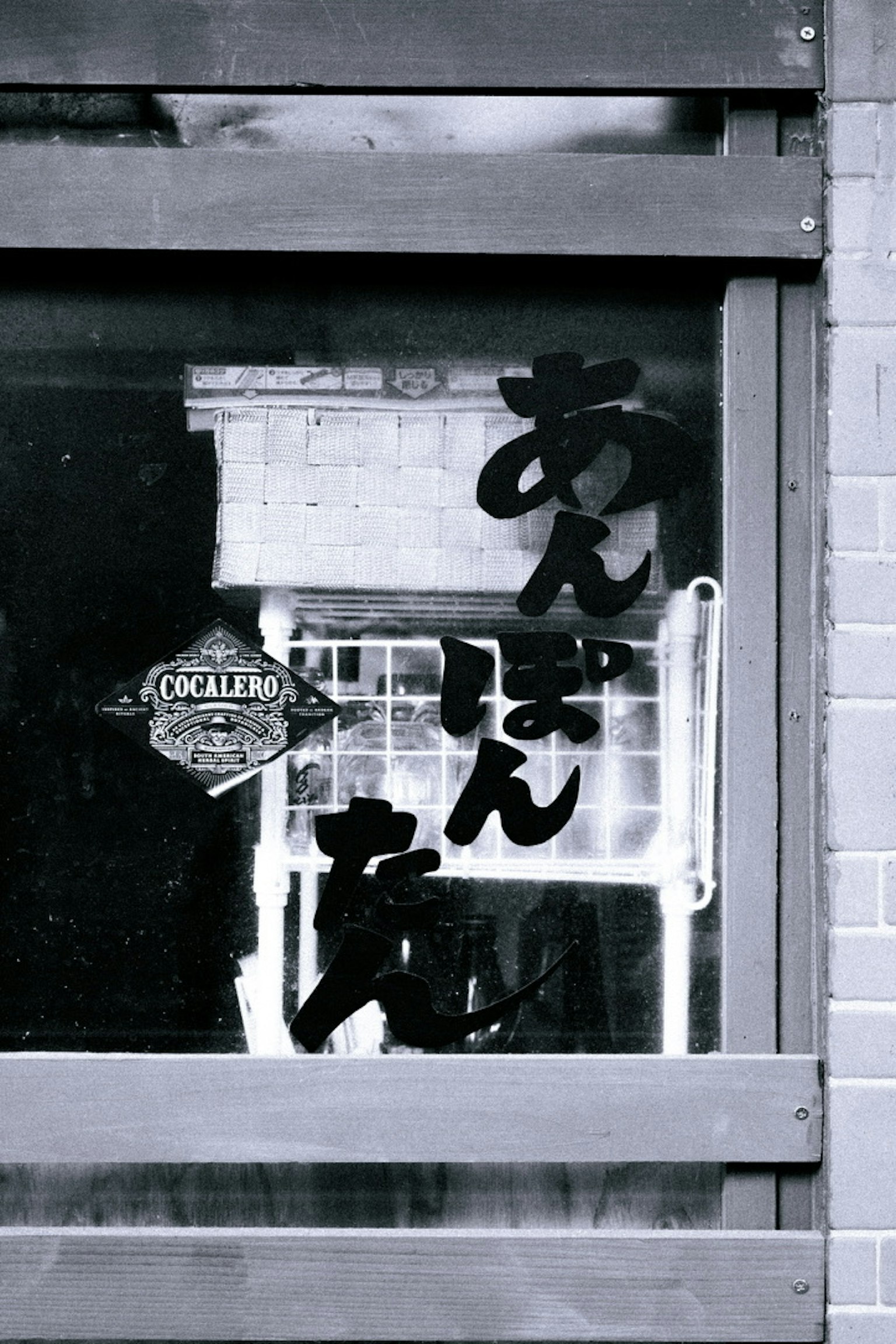 Black and white window featuring Japanese text and a sign for an izakaya