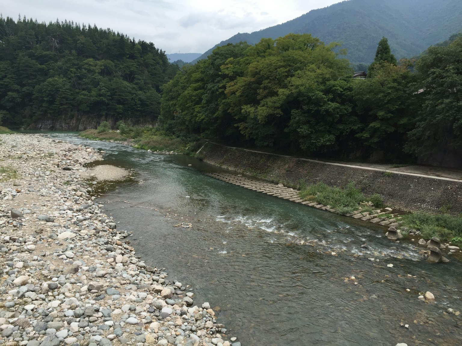 被郁郁葱葱的山脉环绕的风景如画的河流景观，岩石河岸和温和的流动
