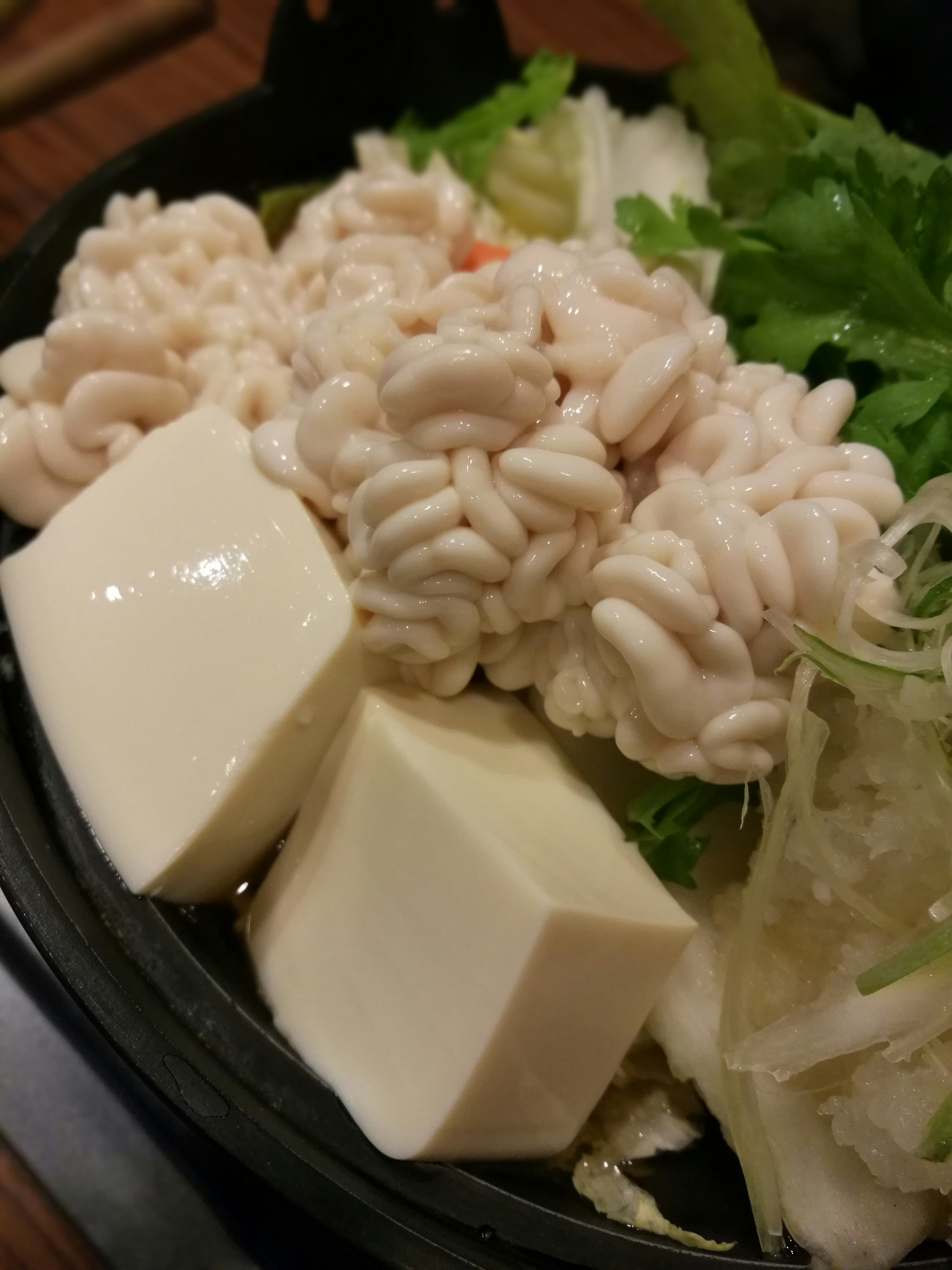 bowl of hot pot with white ingredients, cheese, and lettuce