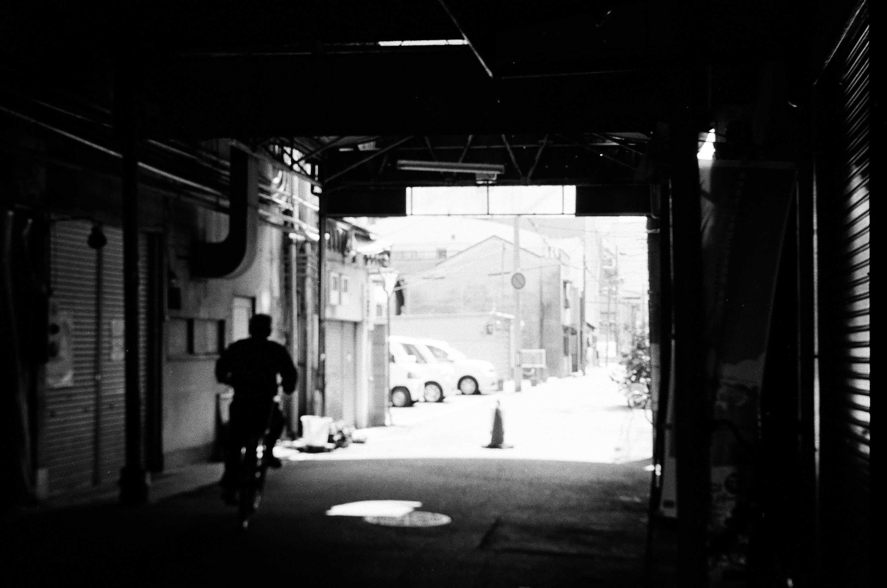 路地のアーケード下を歩く人物のシルエット