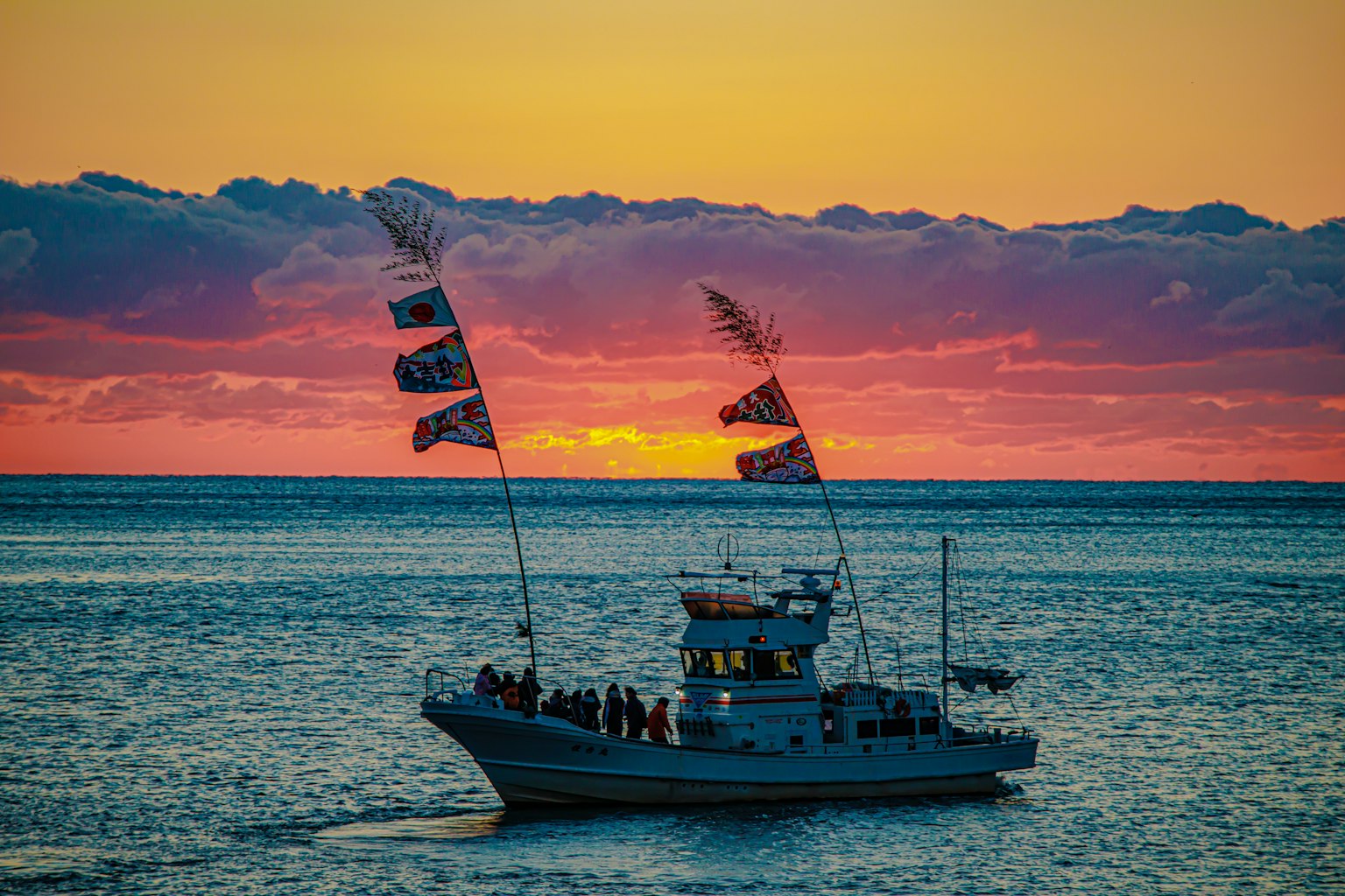 日落海面上漂浮着带旗帜的船的美丽景象