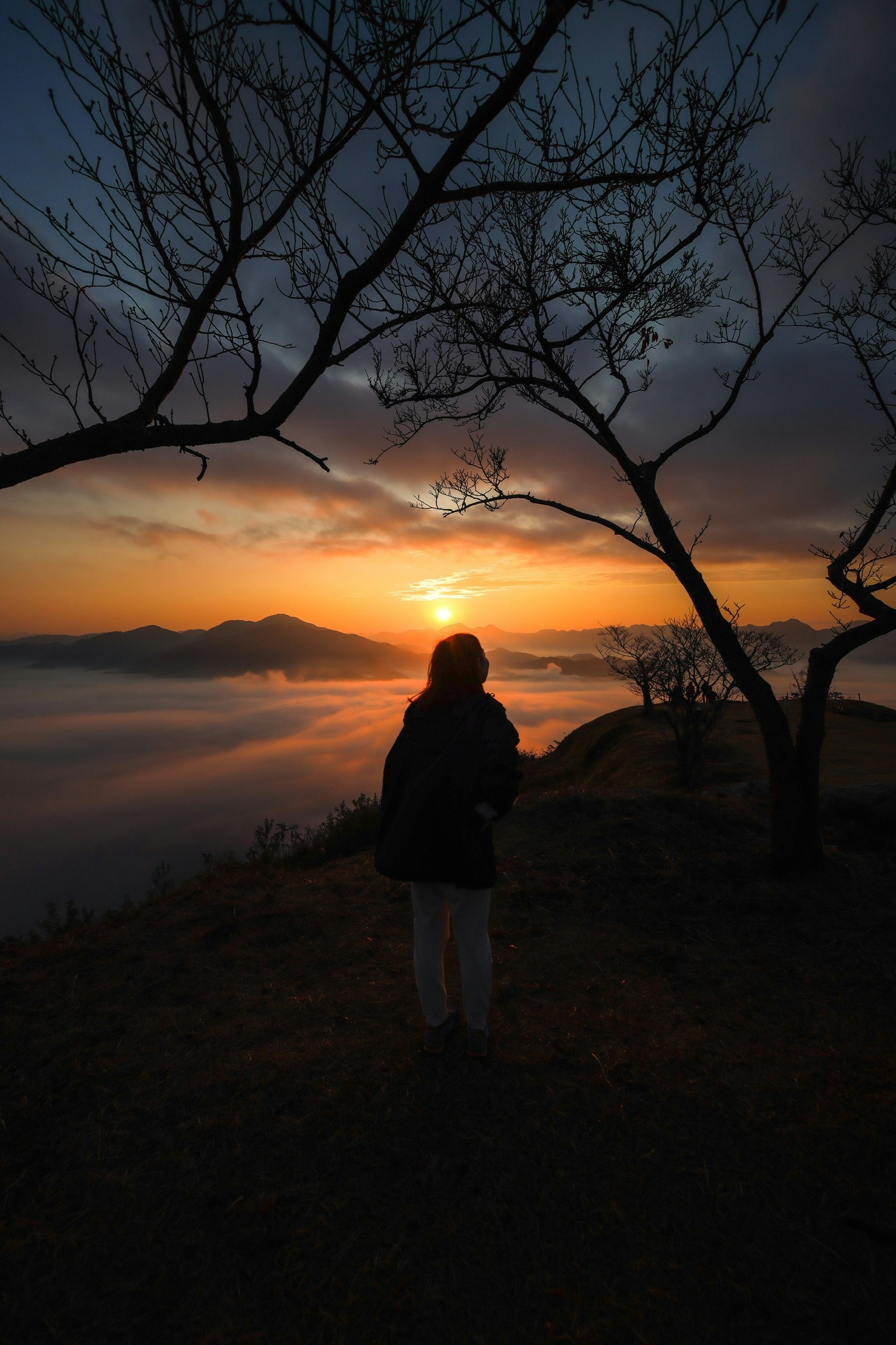 雲海の夕焼けを背に立つ人物のシルエット