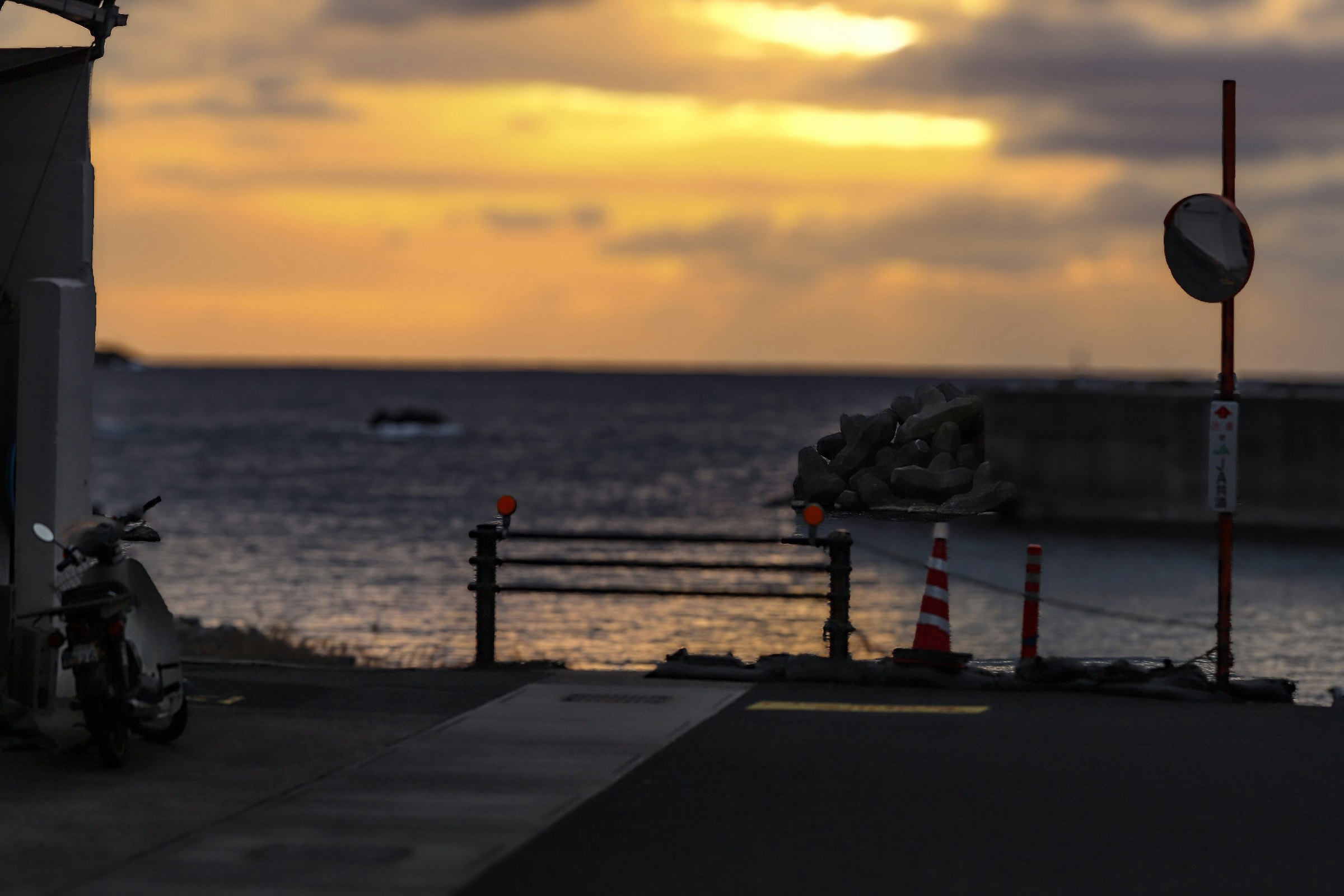 Vista panoramica del mare e del tramonto con una moto e un cartello
