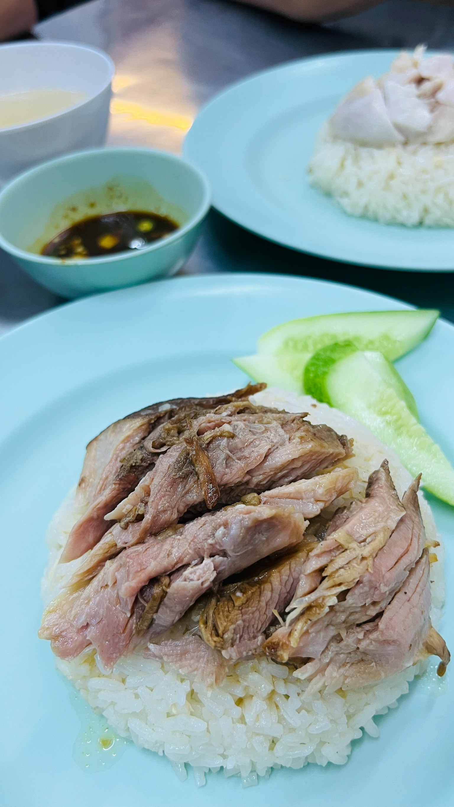 Gericht mit geschnittenem Hähnchen auf Reis mit Gurkenscheiben und Sauce