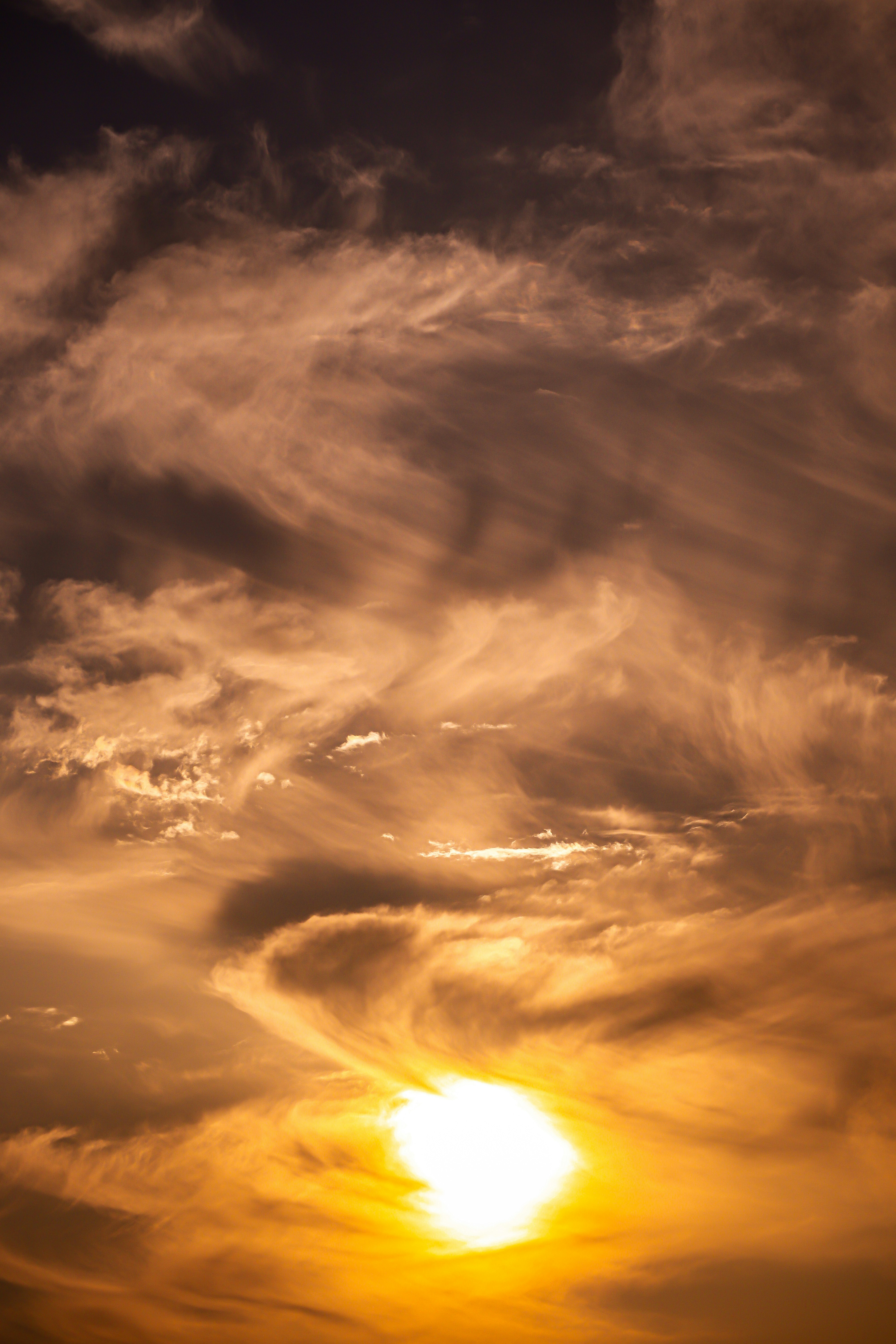 オレンジ色に染まる夕空の雲と太陽