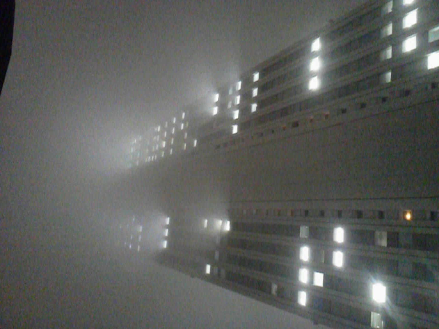 Hochhaus im Nebel mit leuchtenden Fenstern