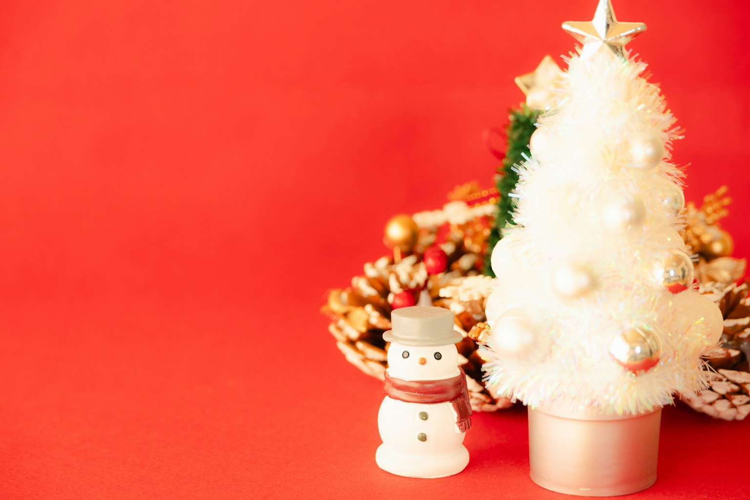 Pohon Natal putih dan manusia salju di latar belakang merah