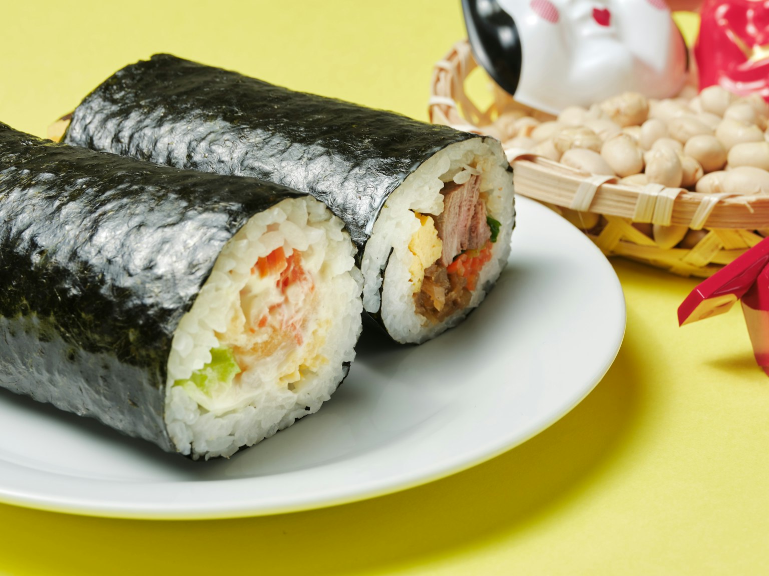 ซูชิโรลบนจานสีขาวกับพื้นหลังสีเหลืองและองค์ประกอบตกแต่ง