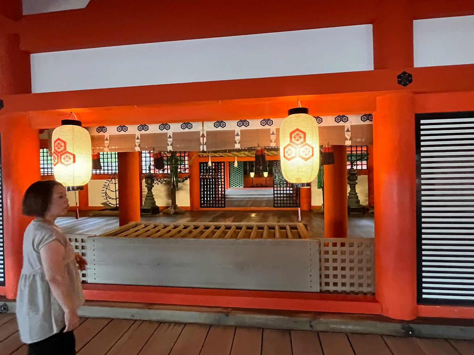 女性观察着一个有红色墙壁和灯笼的神社内部
