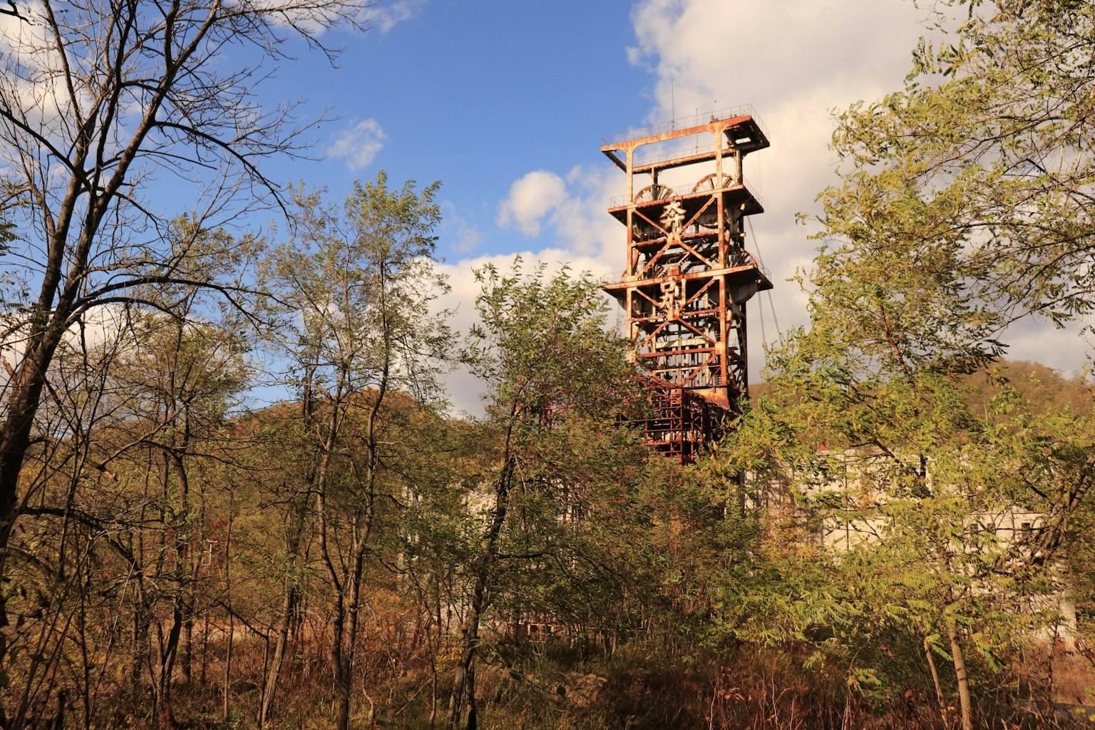 Ein alter Bergwerkturm, der zwischen Bäumen unter einem blauen Himmel aufragt