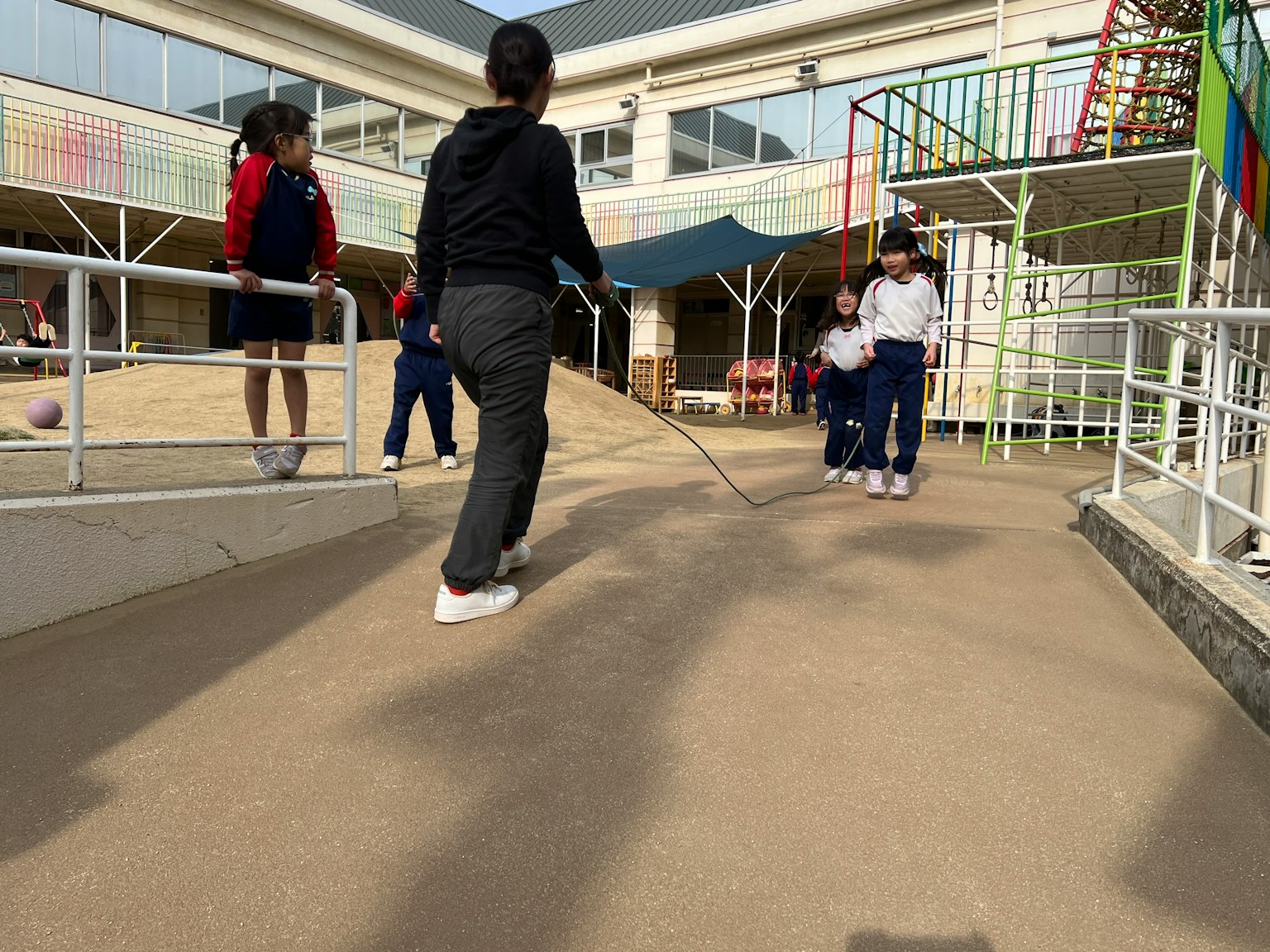 孩子們在學校操場上玩耍，有滑梯和攀爬結構
