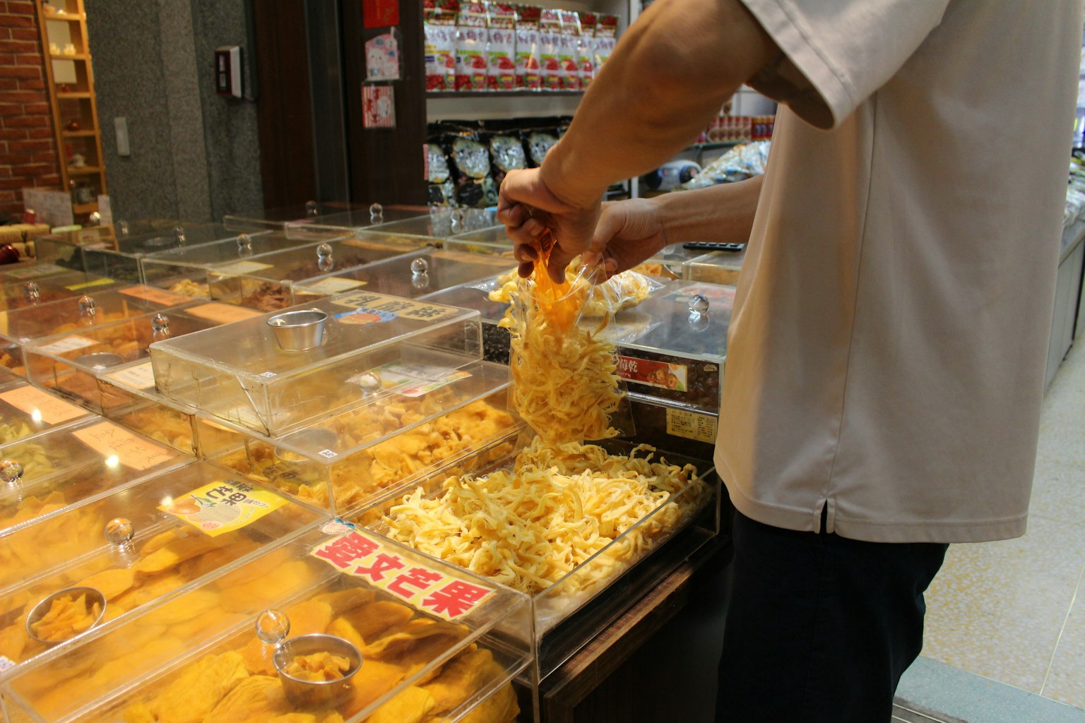 Persona che pesa snack con contenitori trasparenti in un negozio