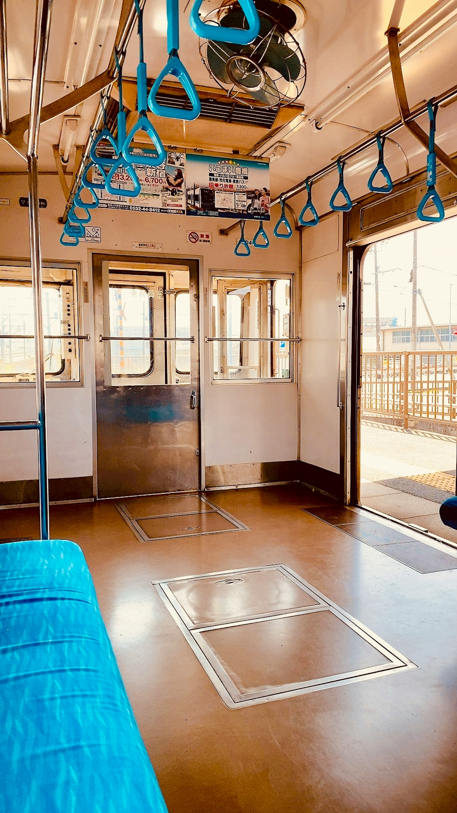 Compartment de tren con pasamanos azules y asientos vacíos