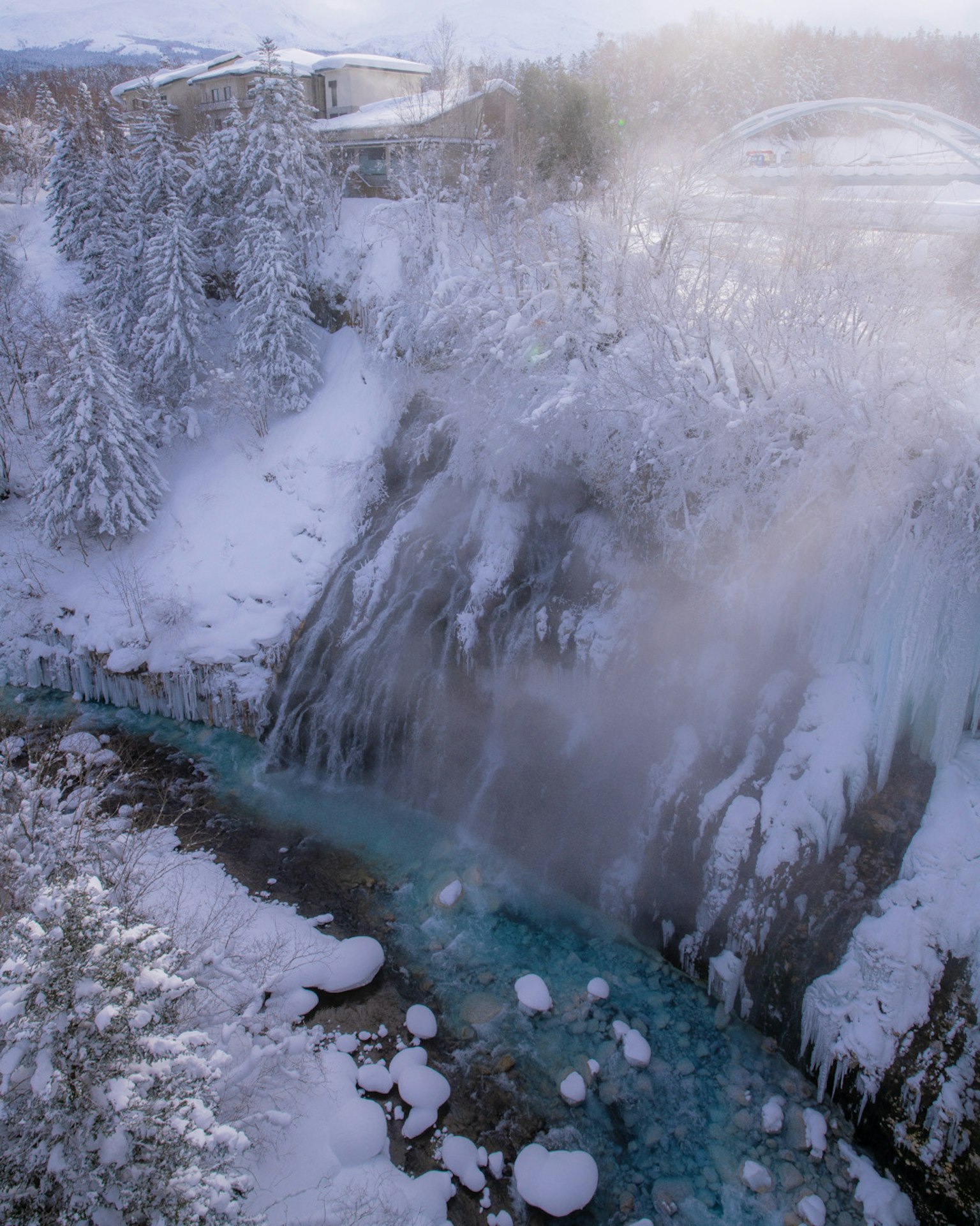 Cascada cubierta de nieve con un río azul