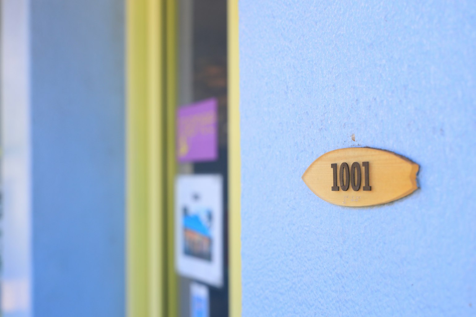 Numéro de chambre 1001 sur une plaque jaune fixée à un mur bleu