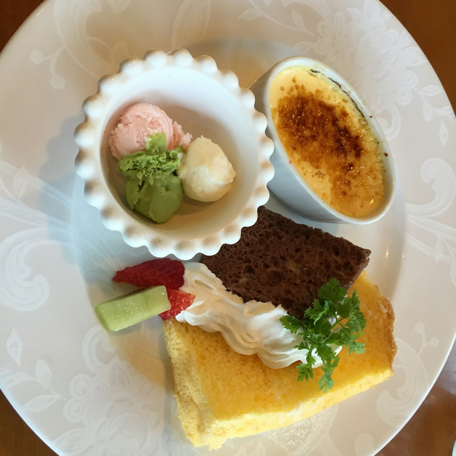 Piatto di dessert con una fetta di torta, gelato e crema brûlée