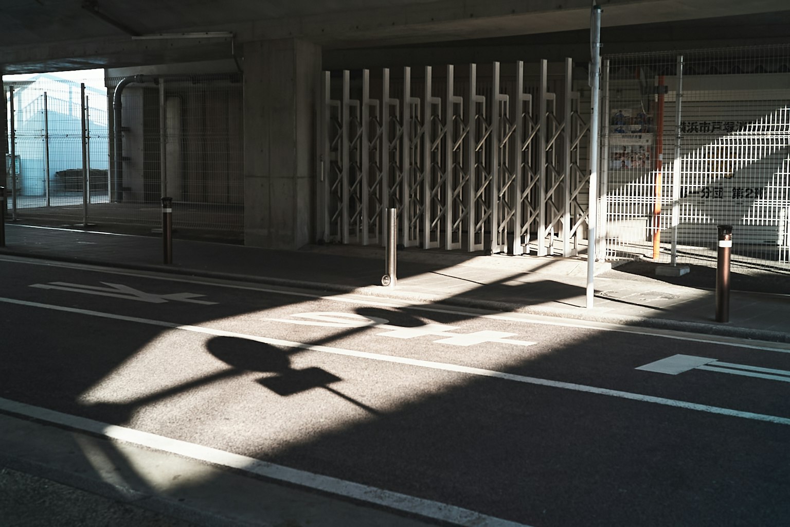 Route avec ombres et structure de clôture