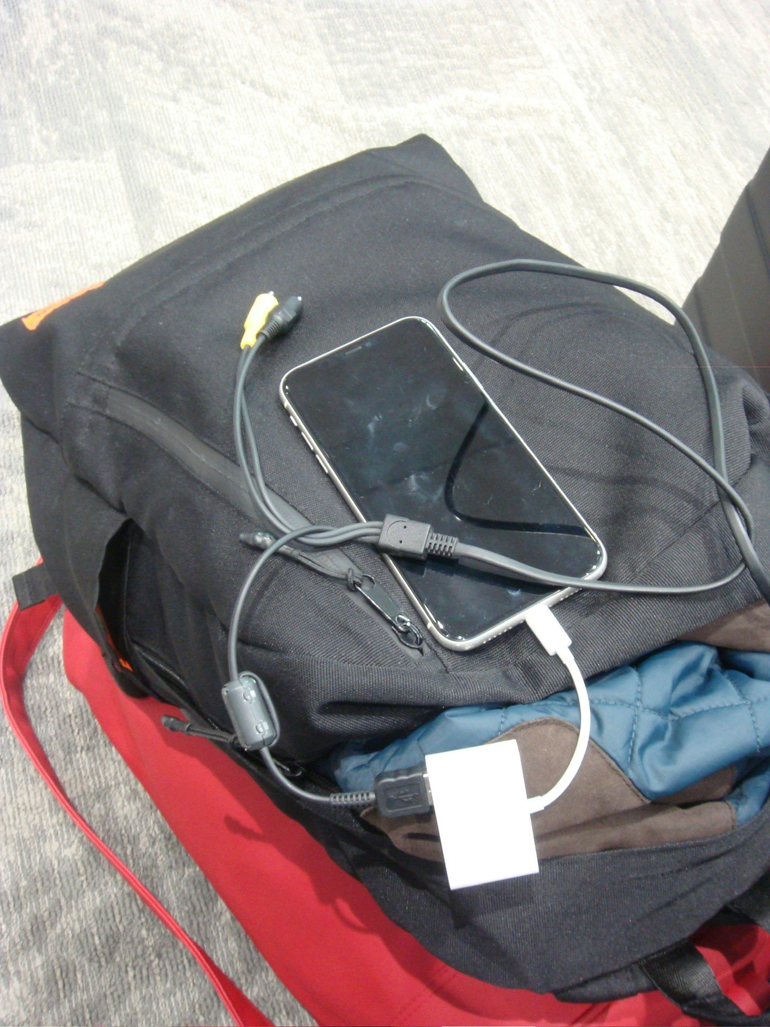 Smartphone and charging cable on top of a black backpack