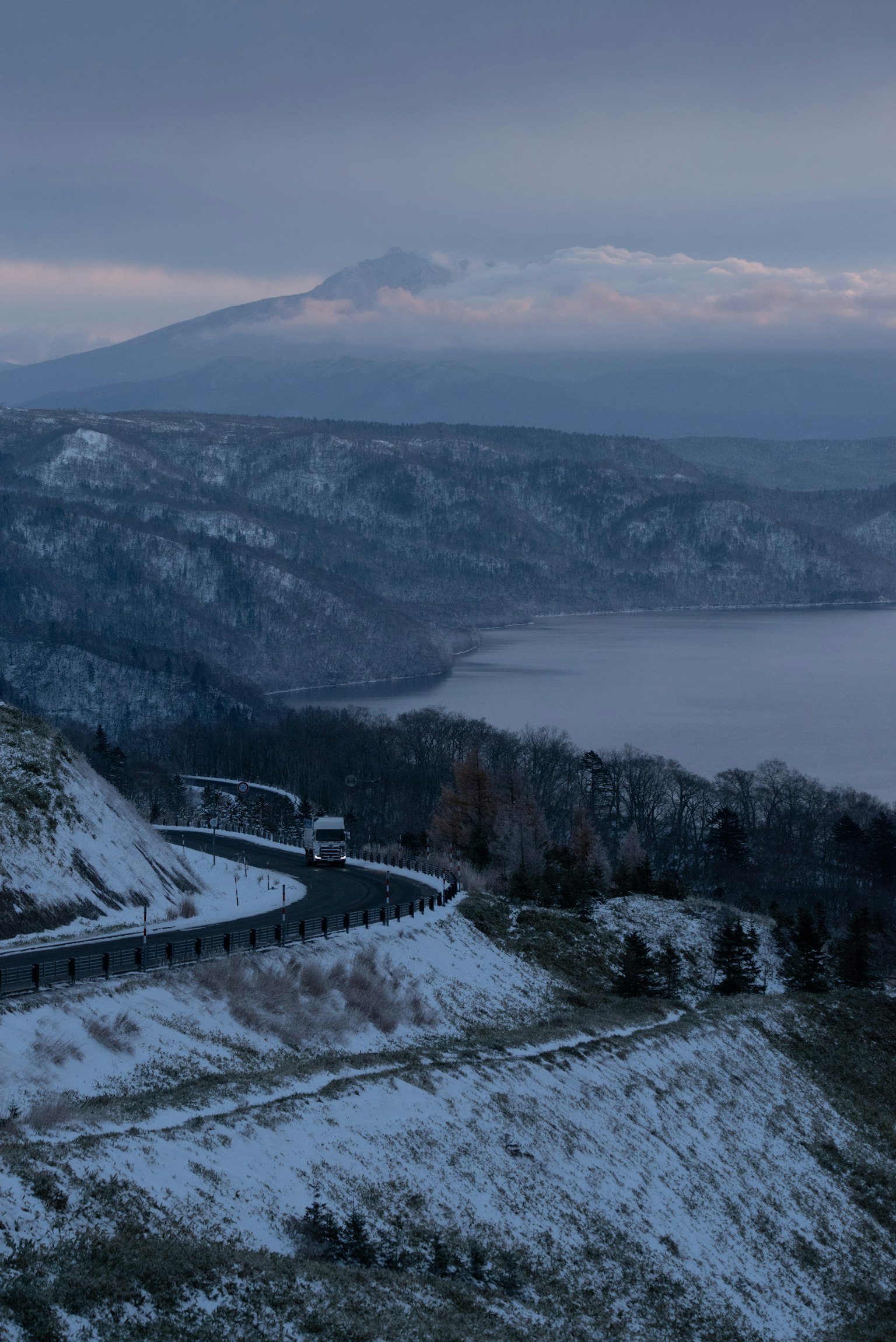 雪に覆われた山道と湖の景色 遠くに山が見える