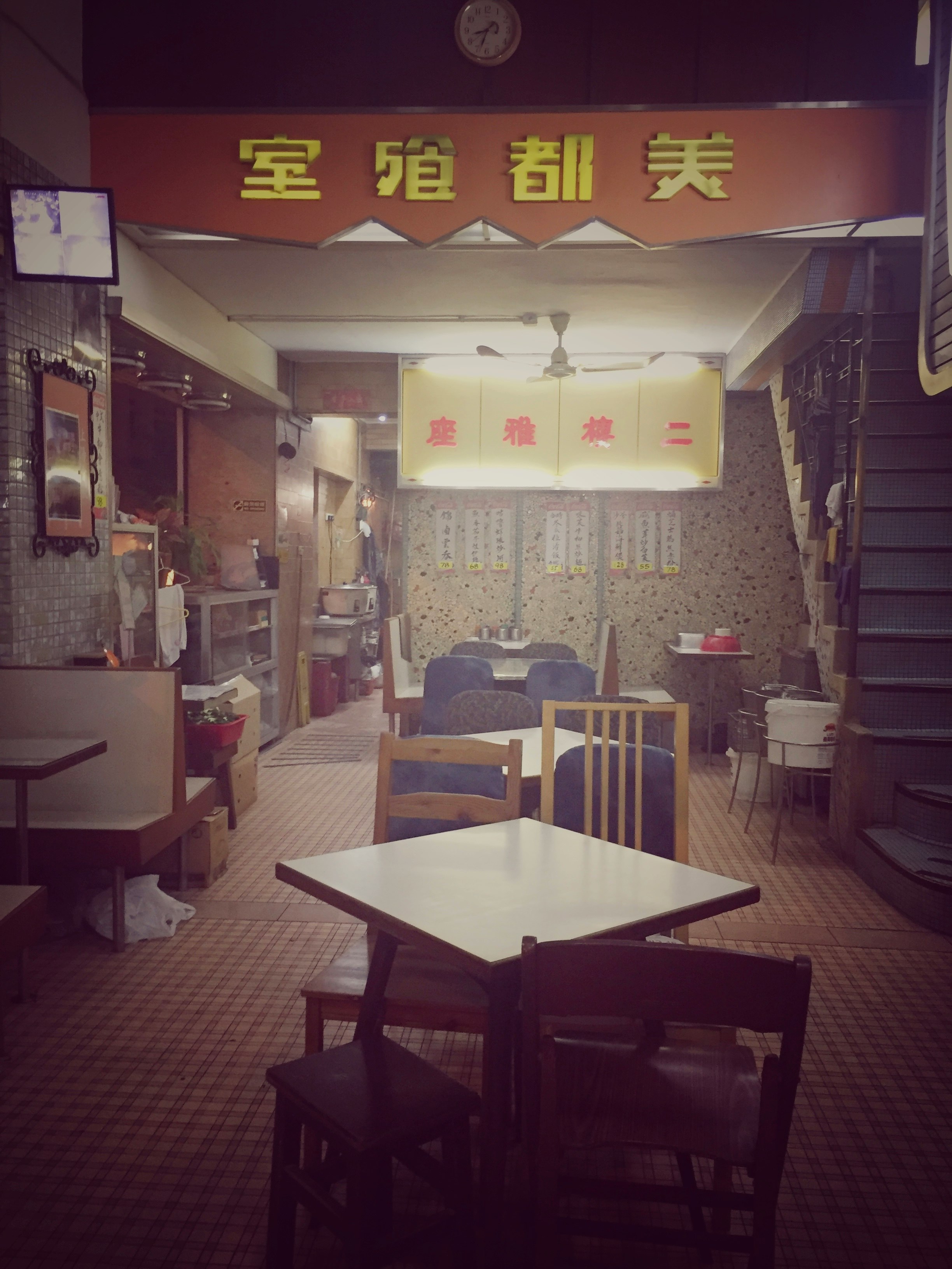 บรรยากาศร้านอาหารสไตล์จีนขนาดเล็กภายใน พร้อมป้ายสีแดงและโต๊ะ