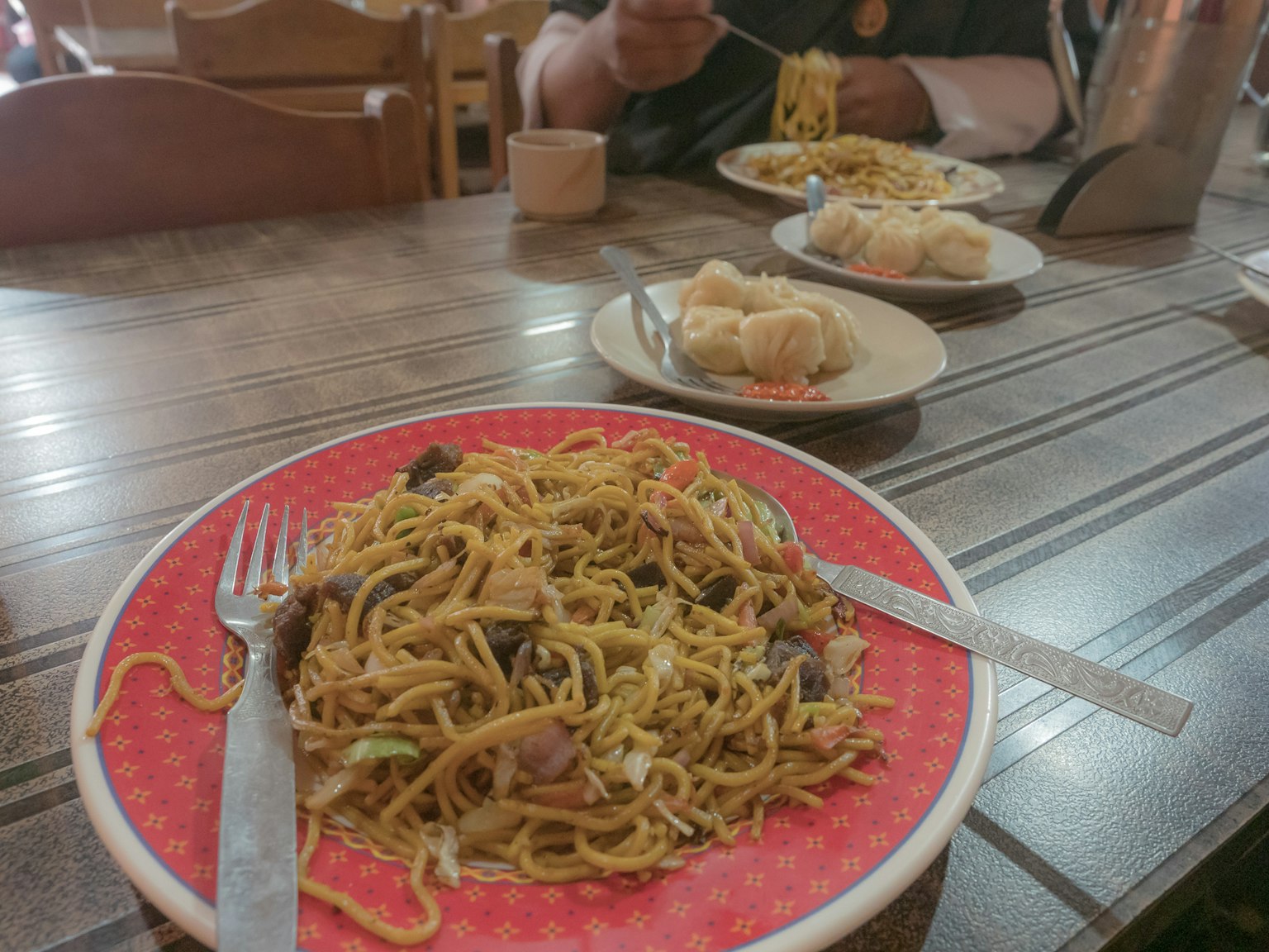 Plato de fideos fritos en una mesa con otros platos al fondo