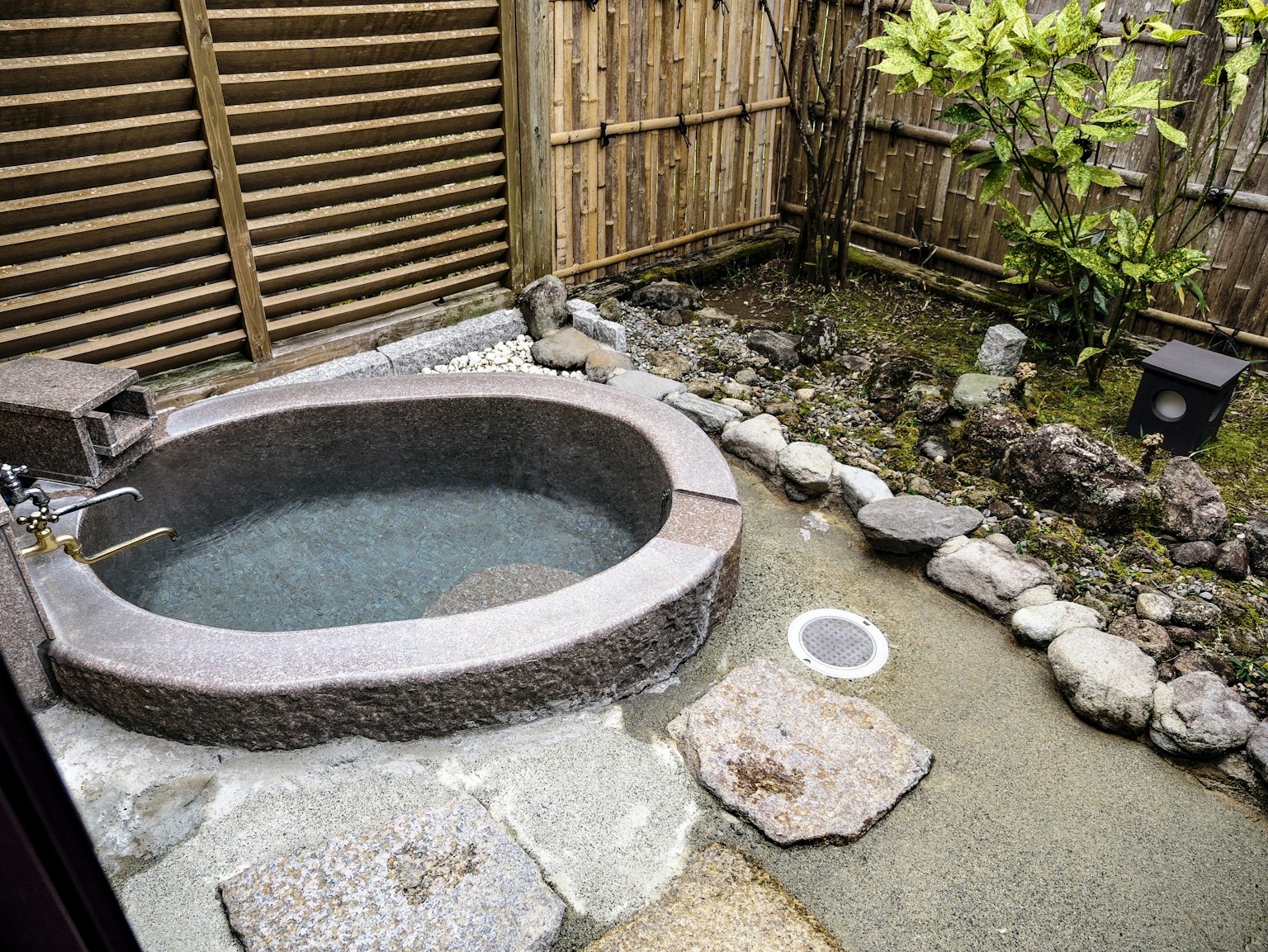 Baño de piedra en un jardín rodeado de elementos naturales