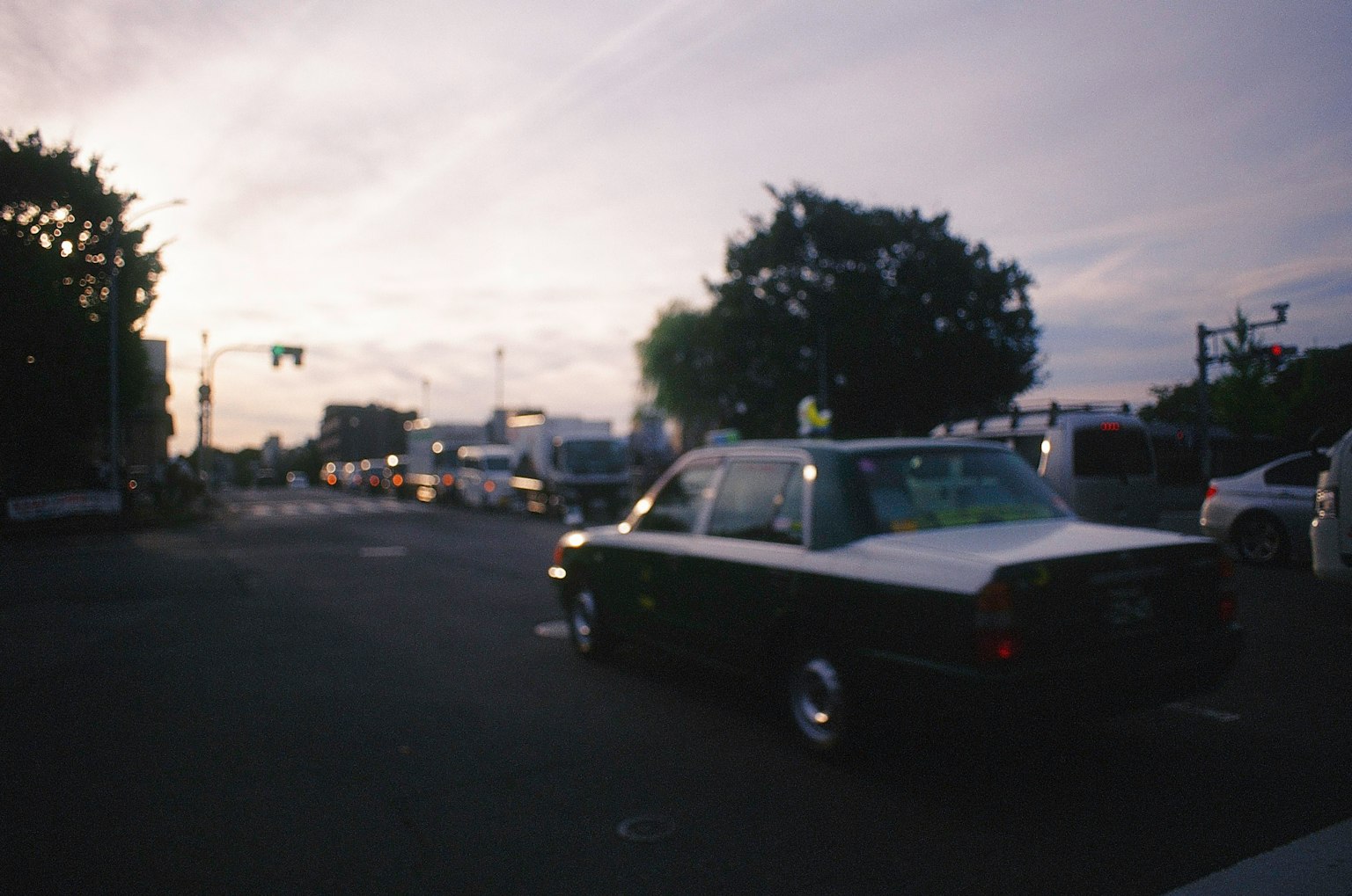 Black and white car parked at an intersection during twilight