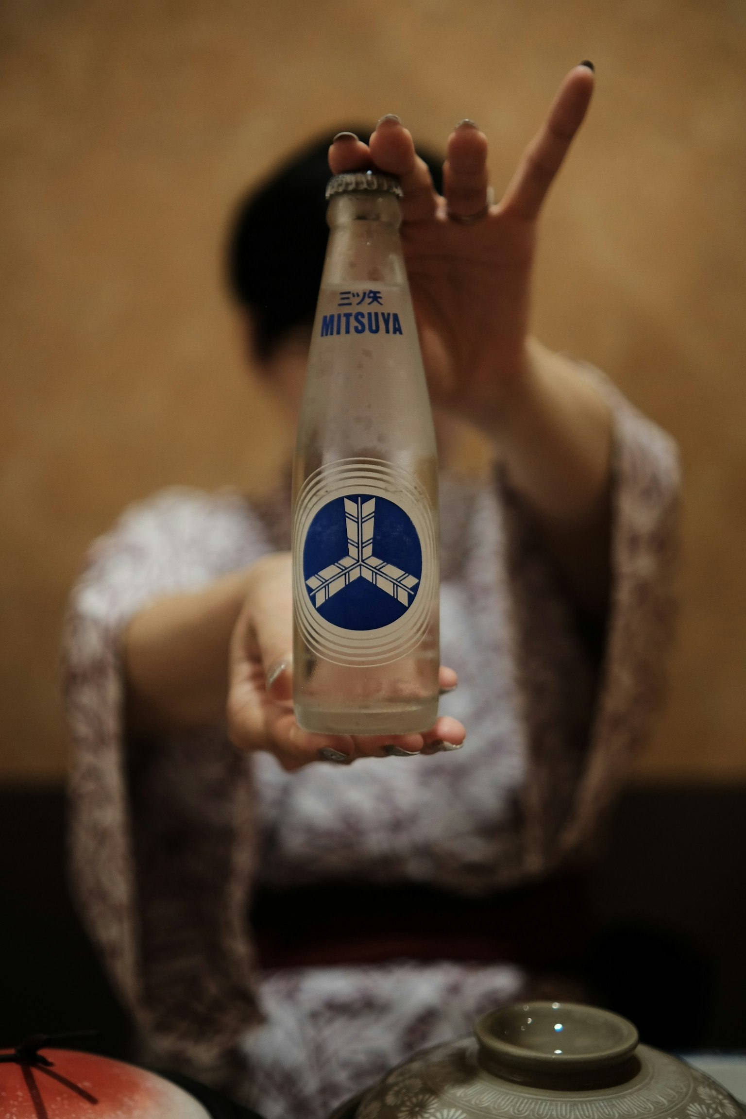 A woman holding a bottle with a blue label in a traditional setting