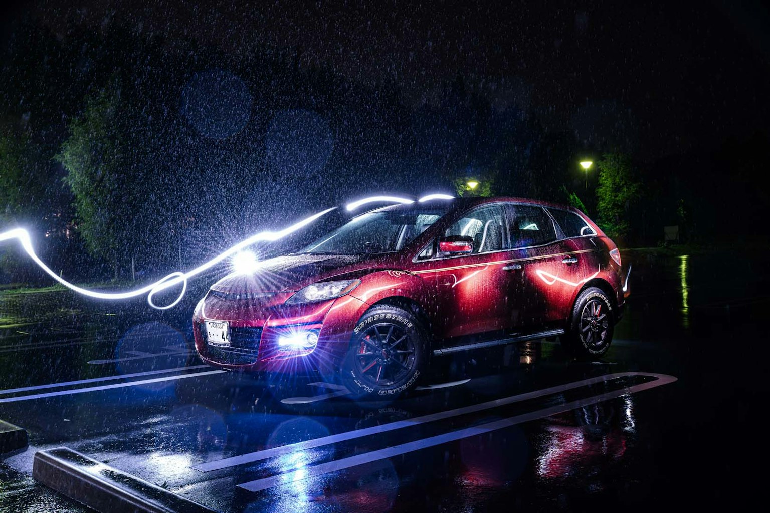 glänzendes rotes Auto im Regen bei Nacht mit Lichtspuren