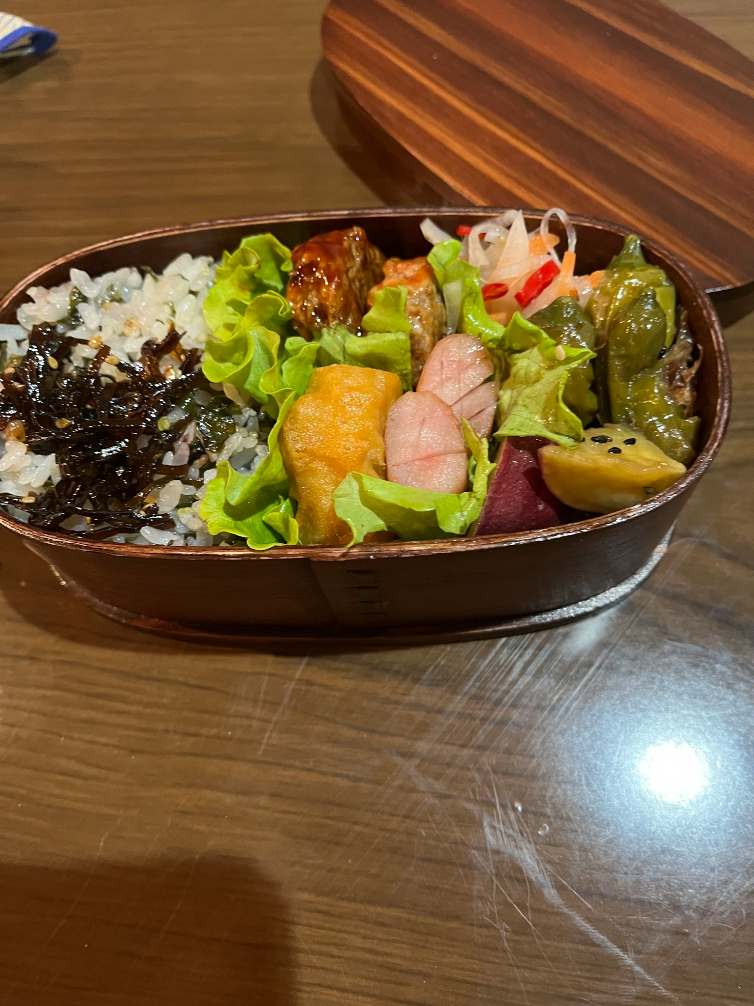 一个装满多彩食材的便当盒，包括米饭、蔬菜和鱼