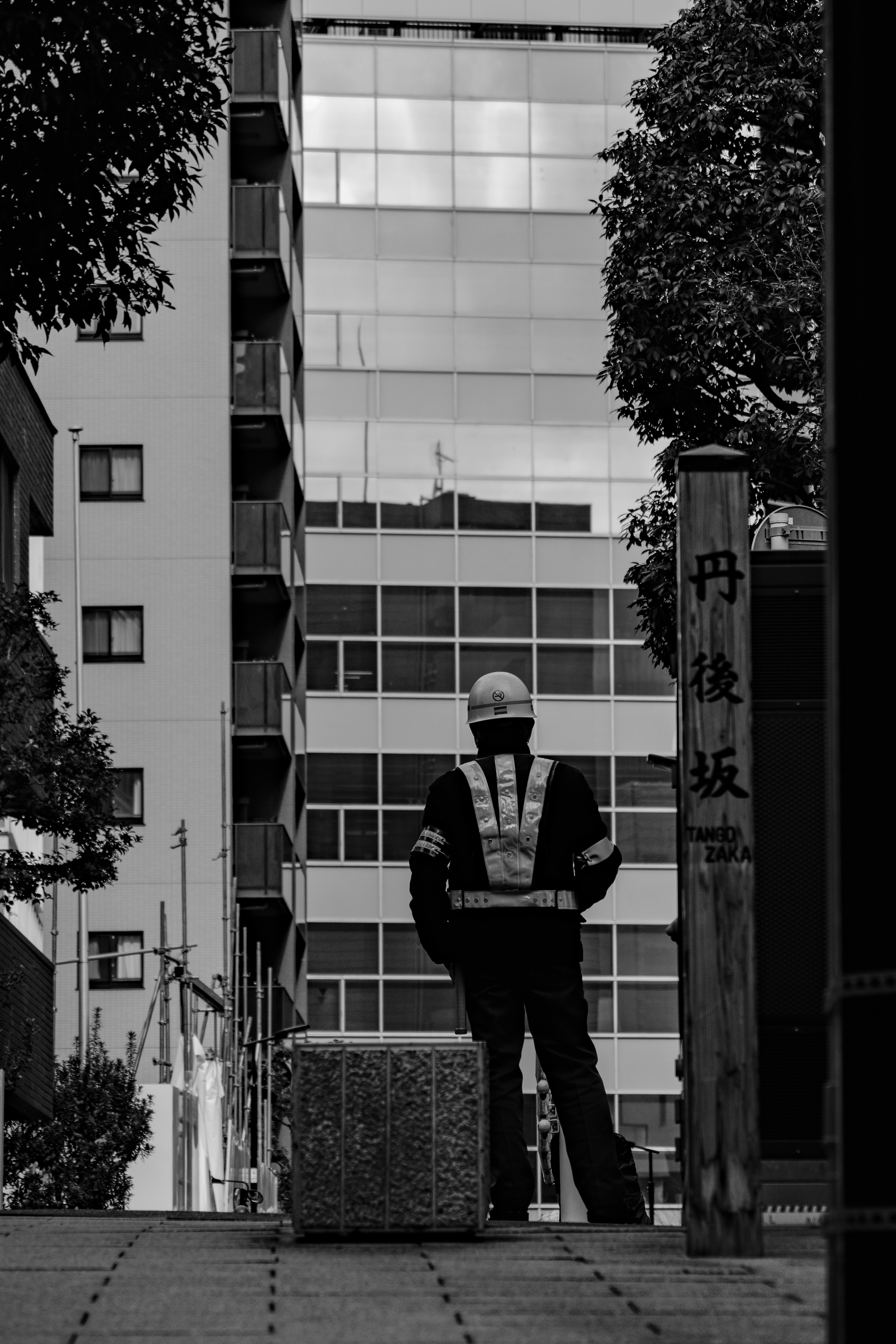 路地の奥に立つスーツ姿の人物とビル群