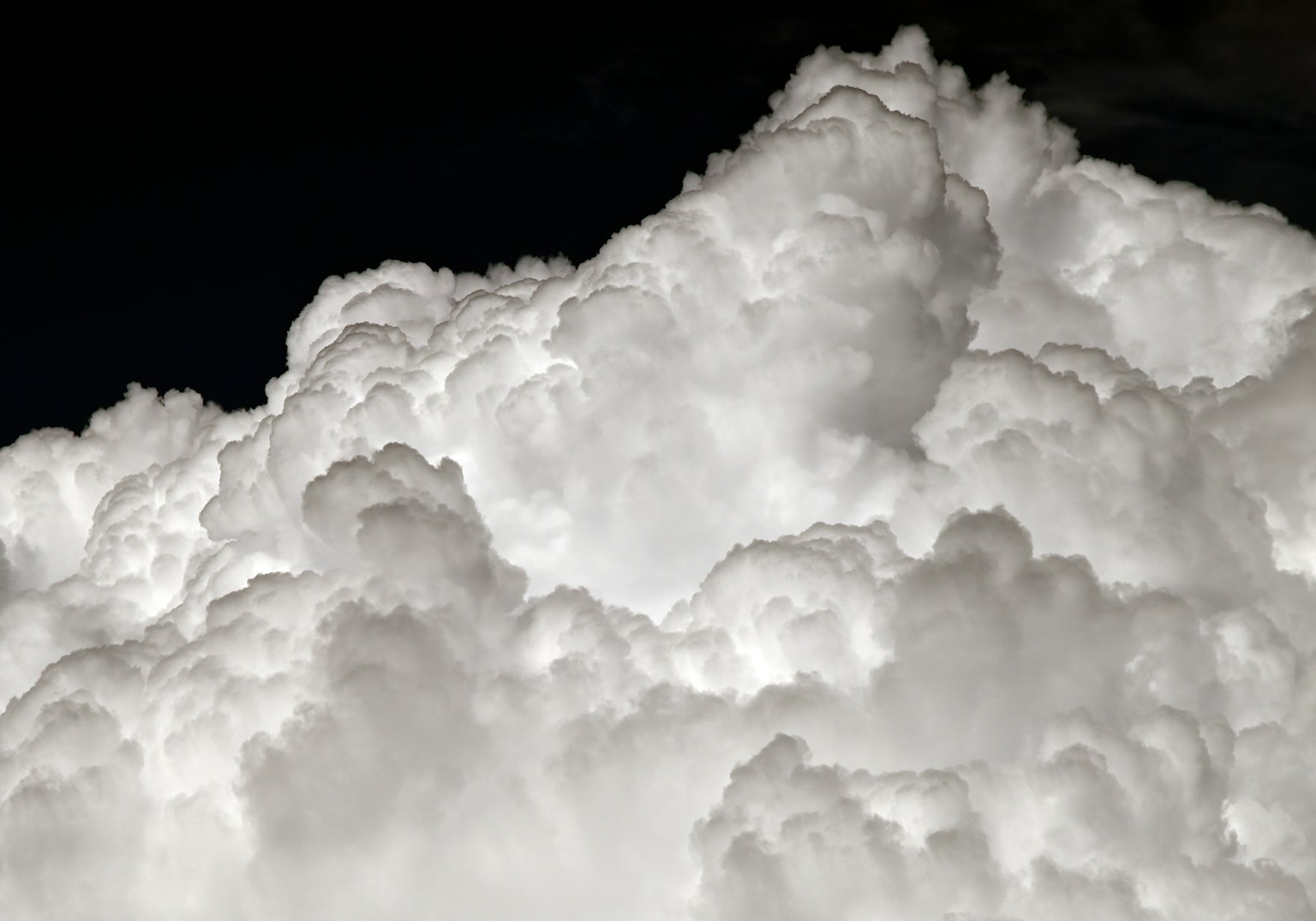 Fluffy white clouds forming a dense mass against a dark background