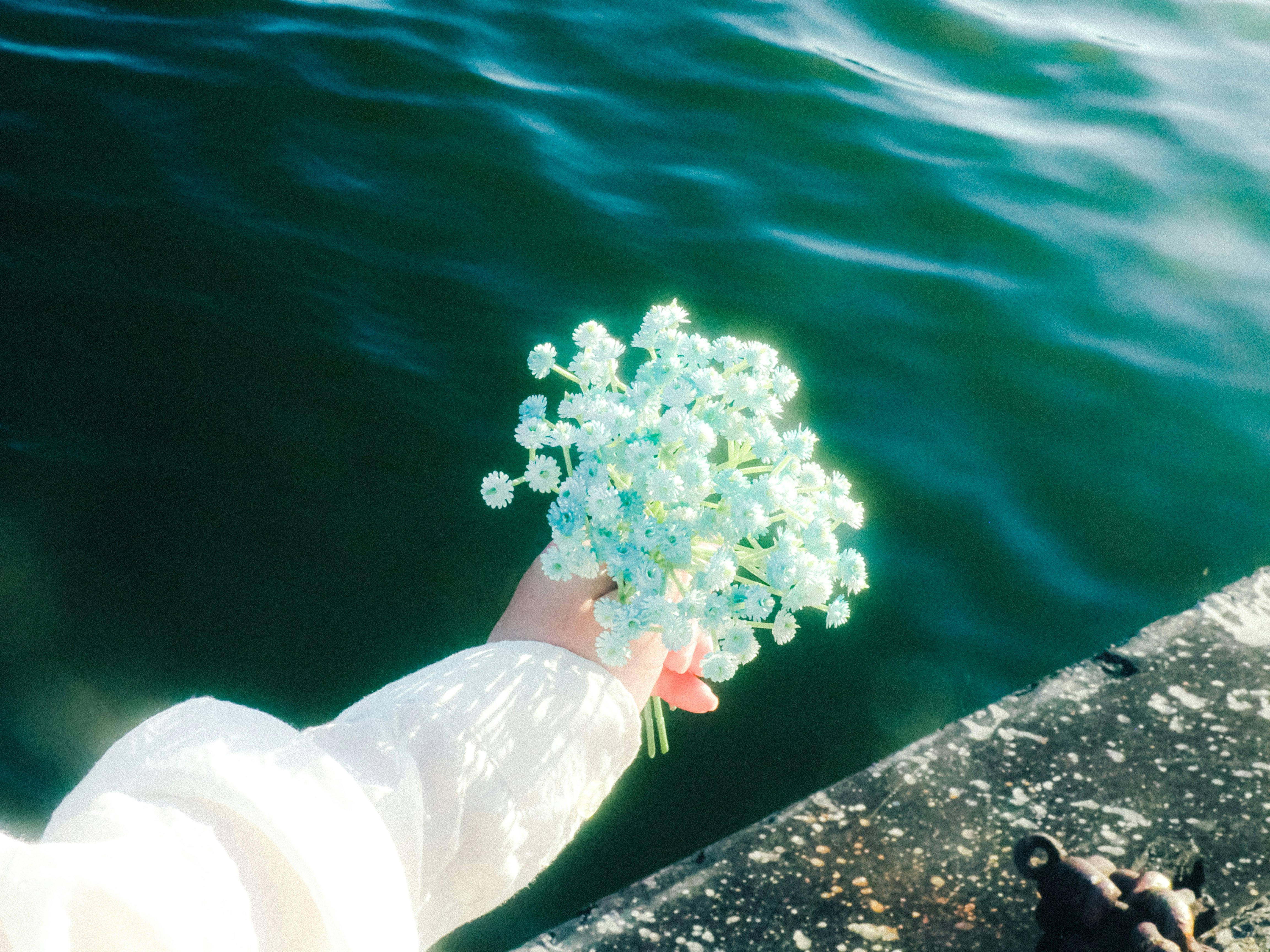 海面に浮かぶ花束を抱える手元